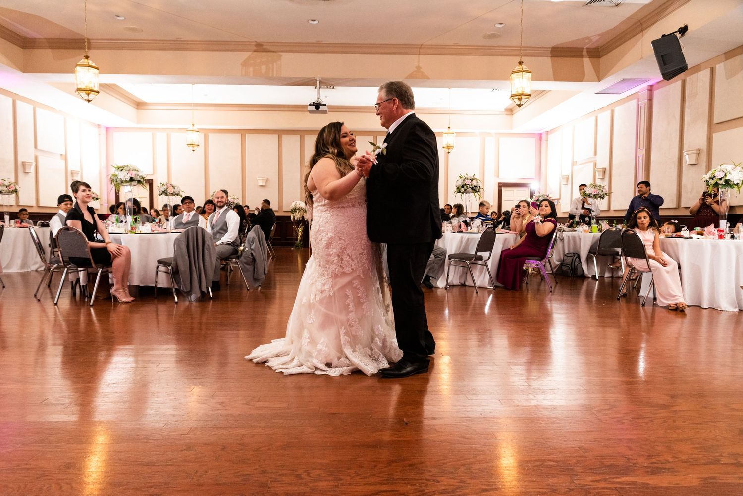 Couple sharing romantic dance on wooden floor at wedding reception.