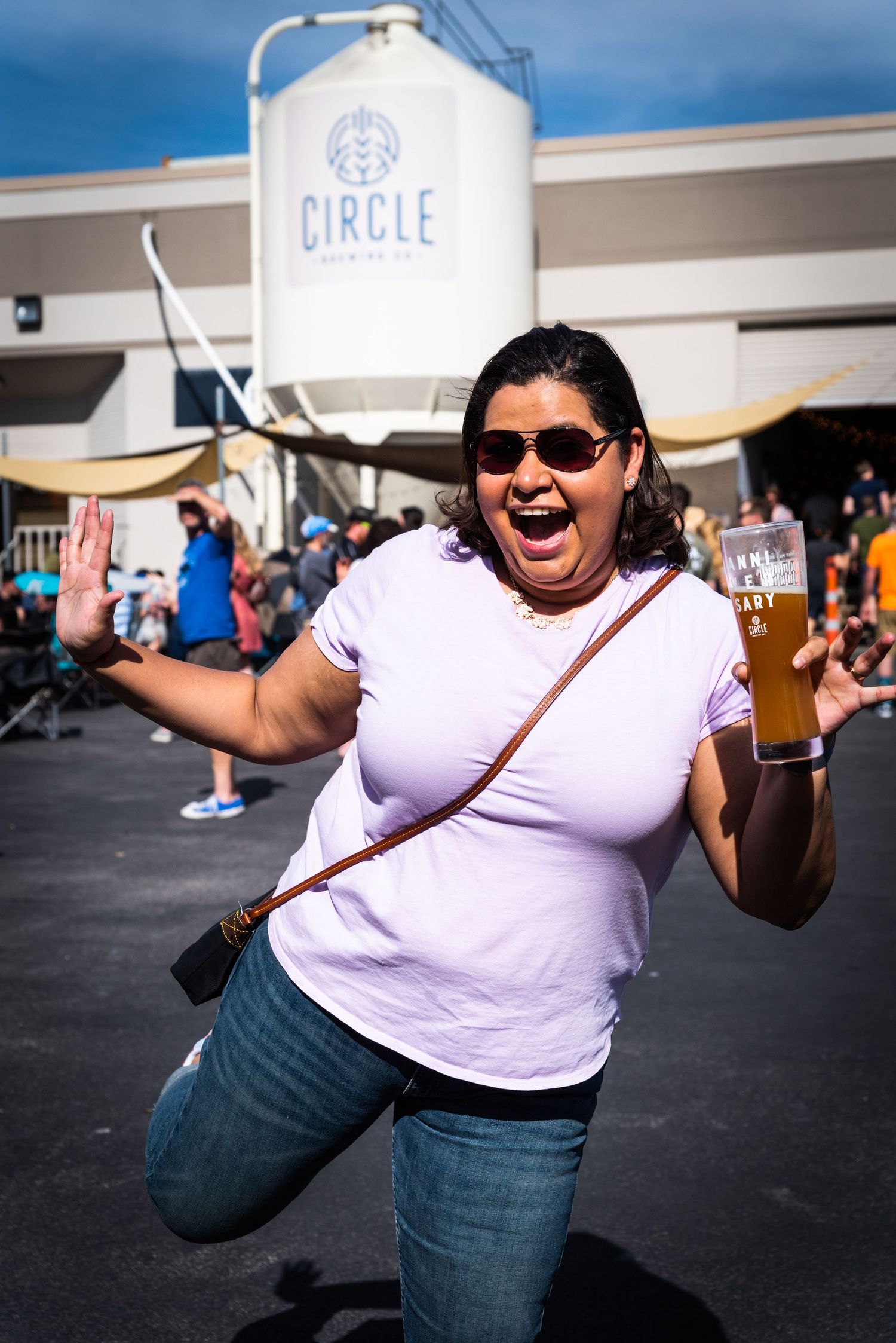 An enthusiastic festival attendee poses with a beer in front of Circle Brewing Company signage.