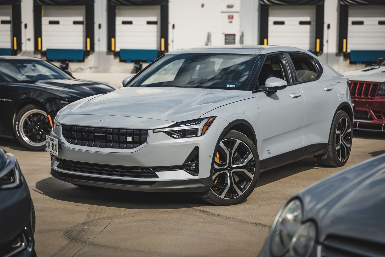 White Polestar 2 electric vehicle parked in front of industrial loading dock doors.