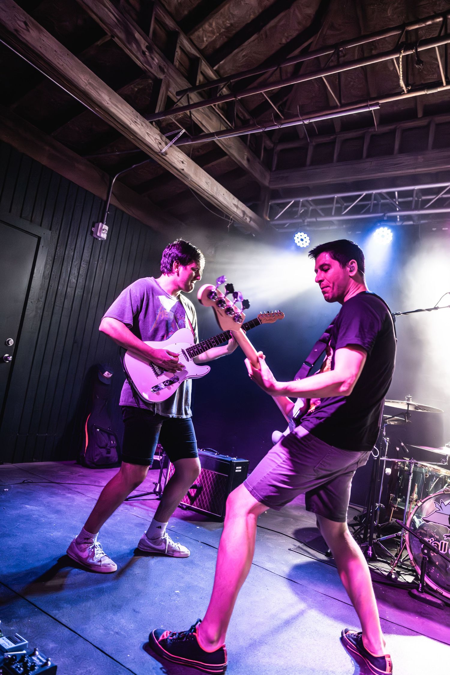 Two musicians performing together on stage under purple lighting effects.