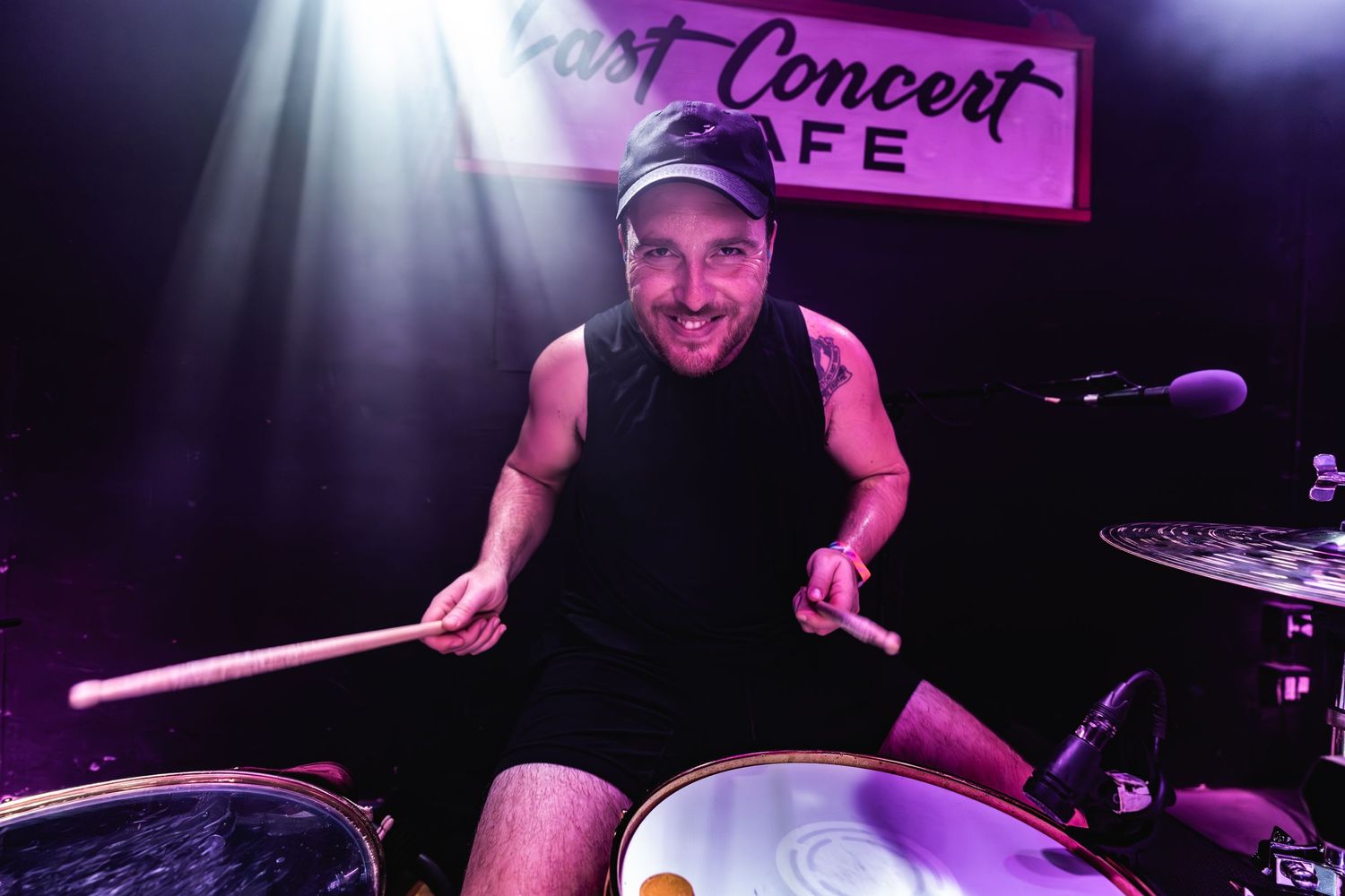 Drummer performs enthusiastically under spotlight at Post Concert Cafe venue.