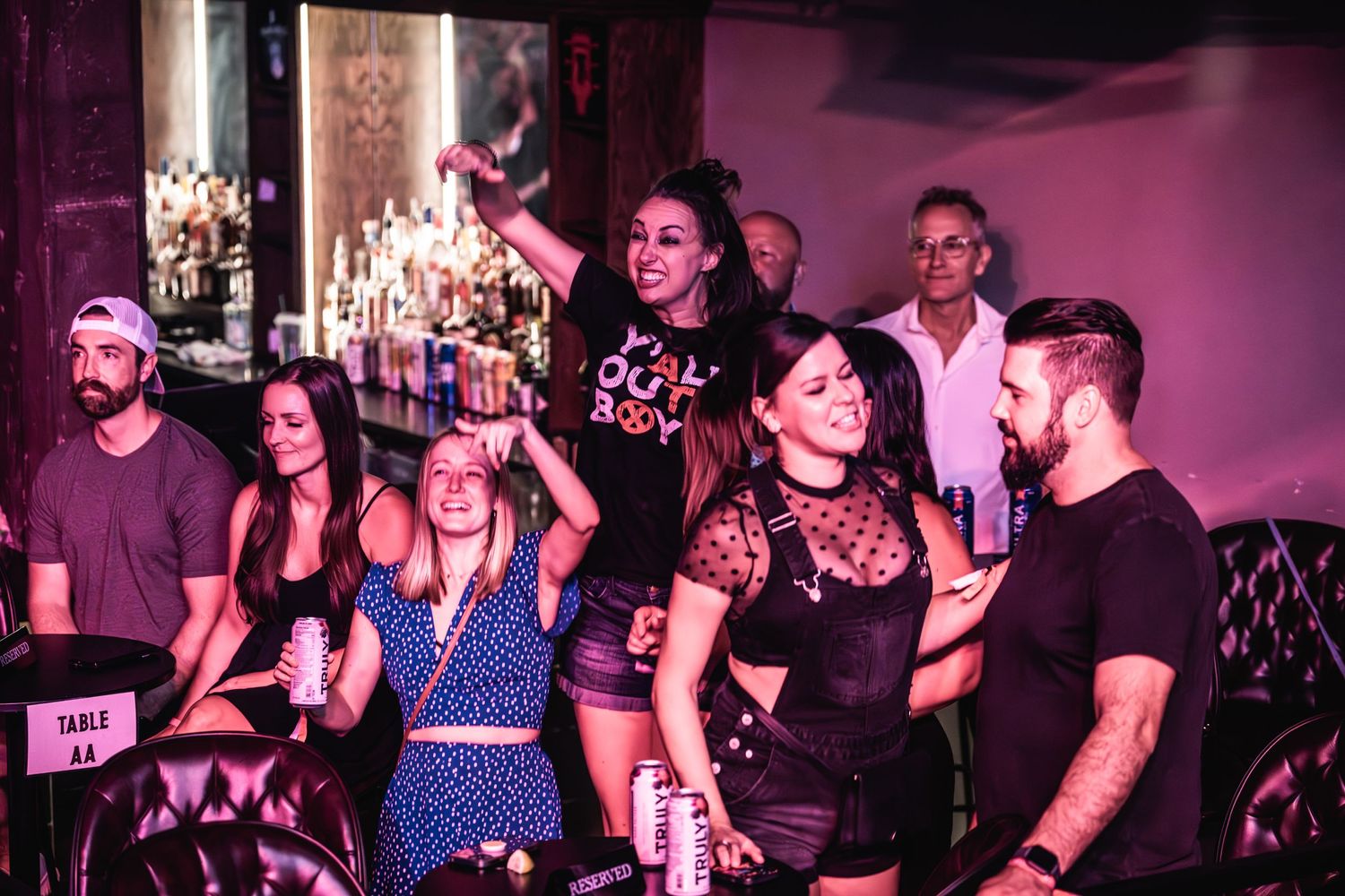 Concert audience enjoying nightclub atmosphere with colorful lighting.