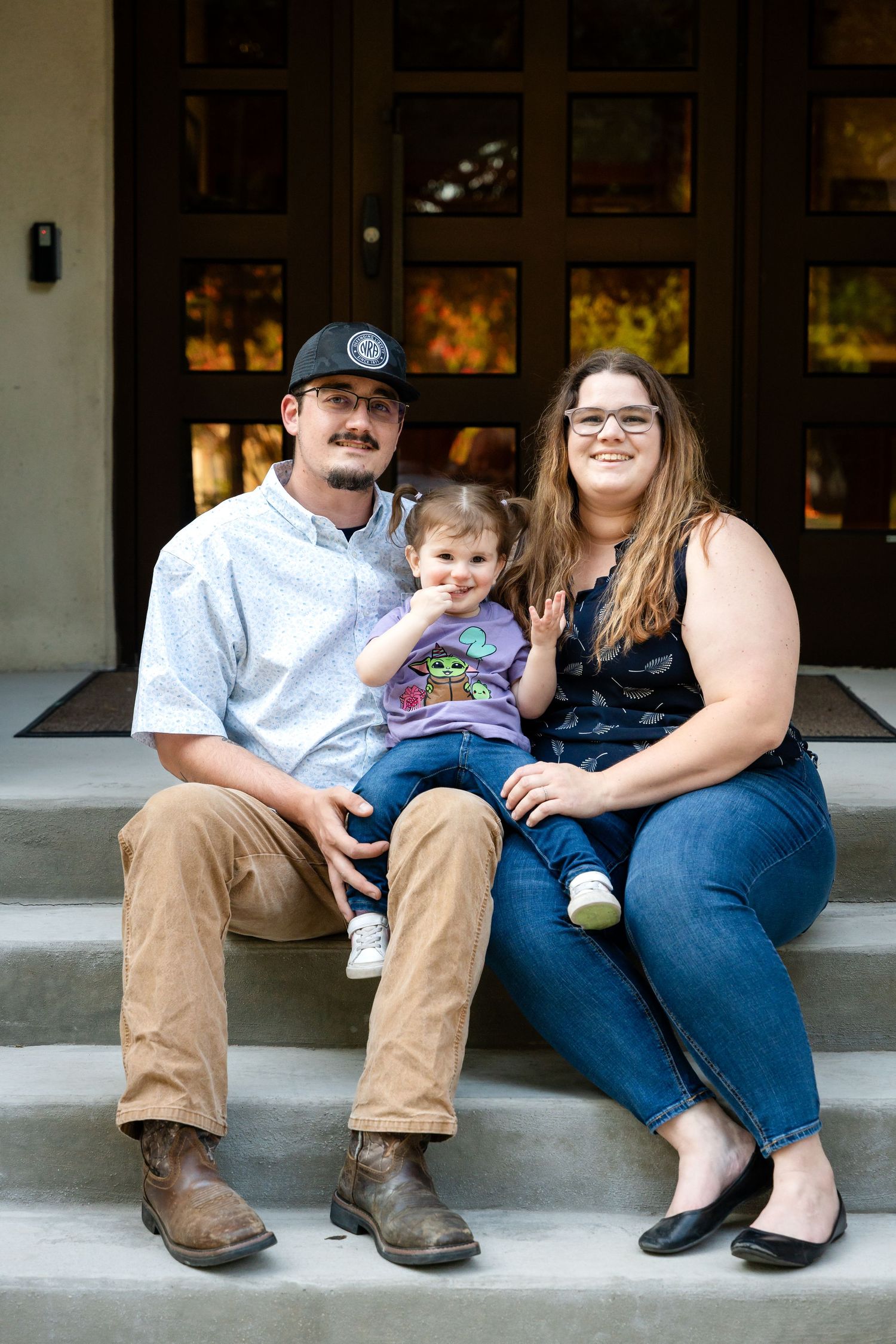 Family poses for portrait while sitting on outdoor steps.
