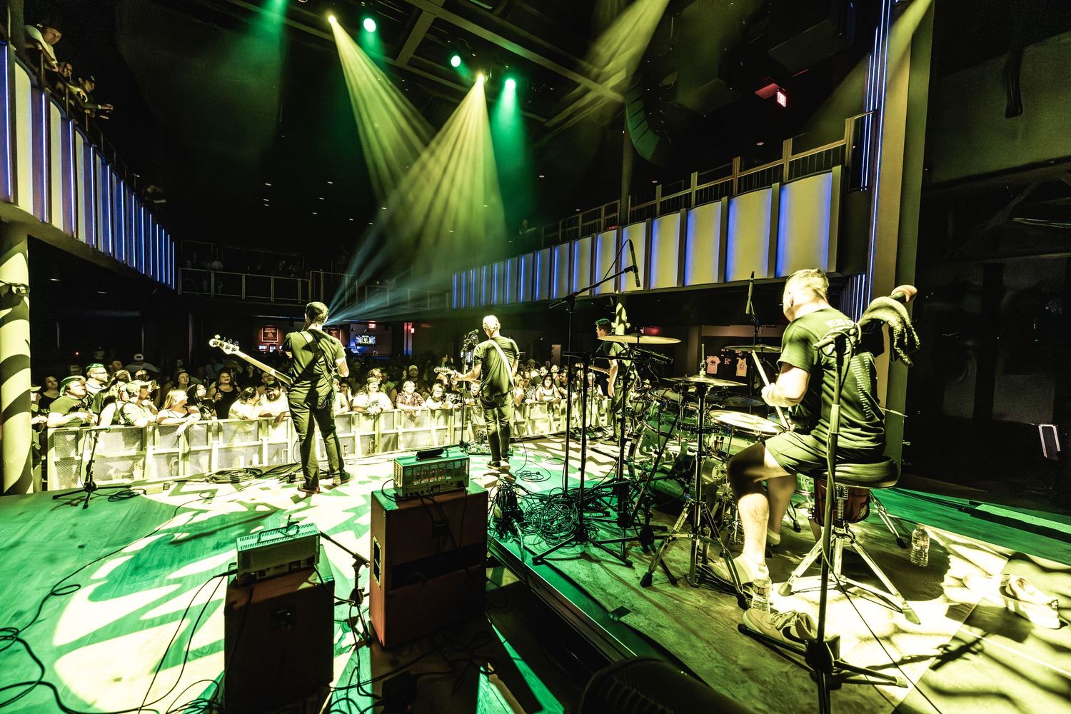 Band performs on stage under dramatic green spotlights with theatrical lighting effects.