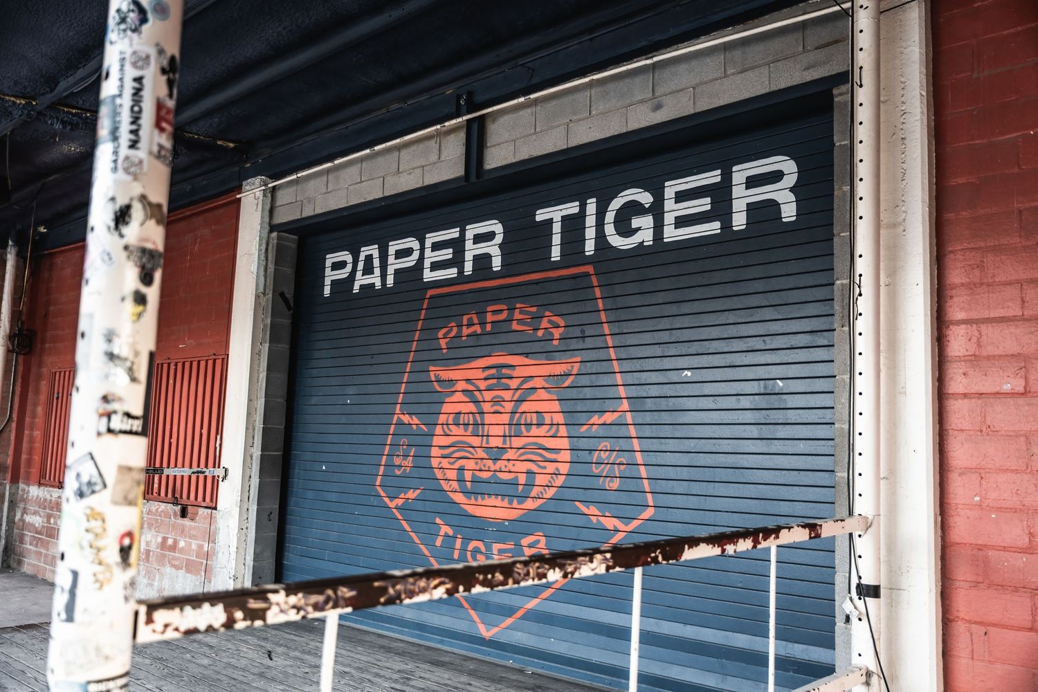 A storefront with 'PAPER TIGER' text and logo on a closed metal security gate.