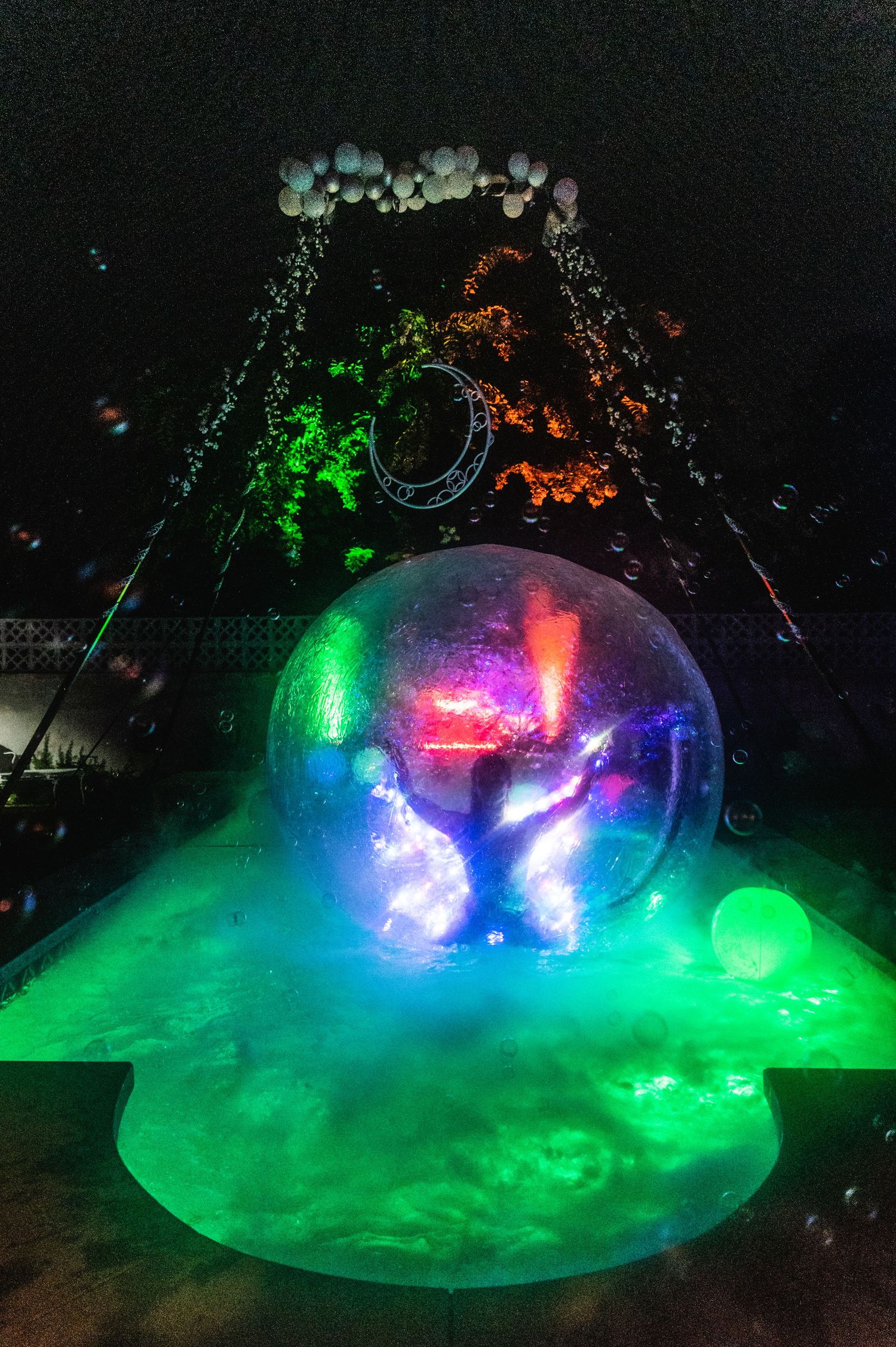 Illuminated sphere performance with multicolored lights and fog creates magical atmosphere.