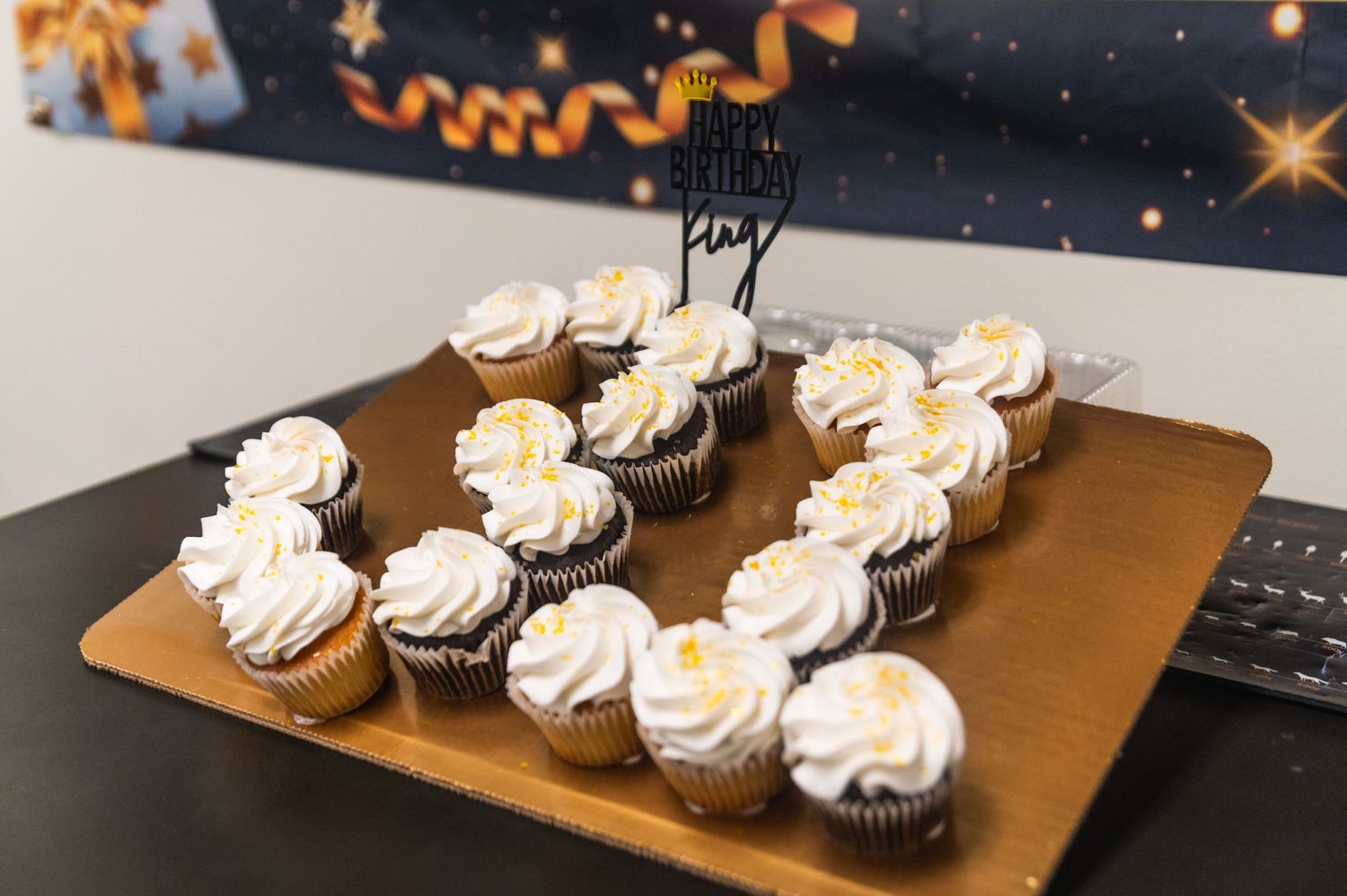 White frosted cupcakes arranged in a heart shape on a gold serving tray.