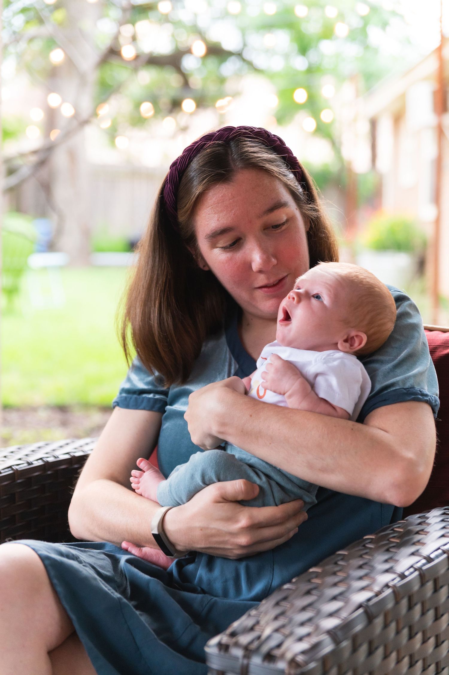 A tender moment of a mother cradling a small infant while sitting on outdoor furniture.
