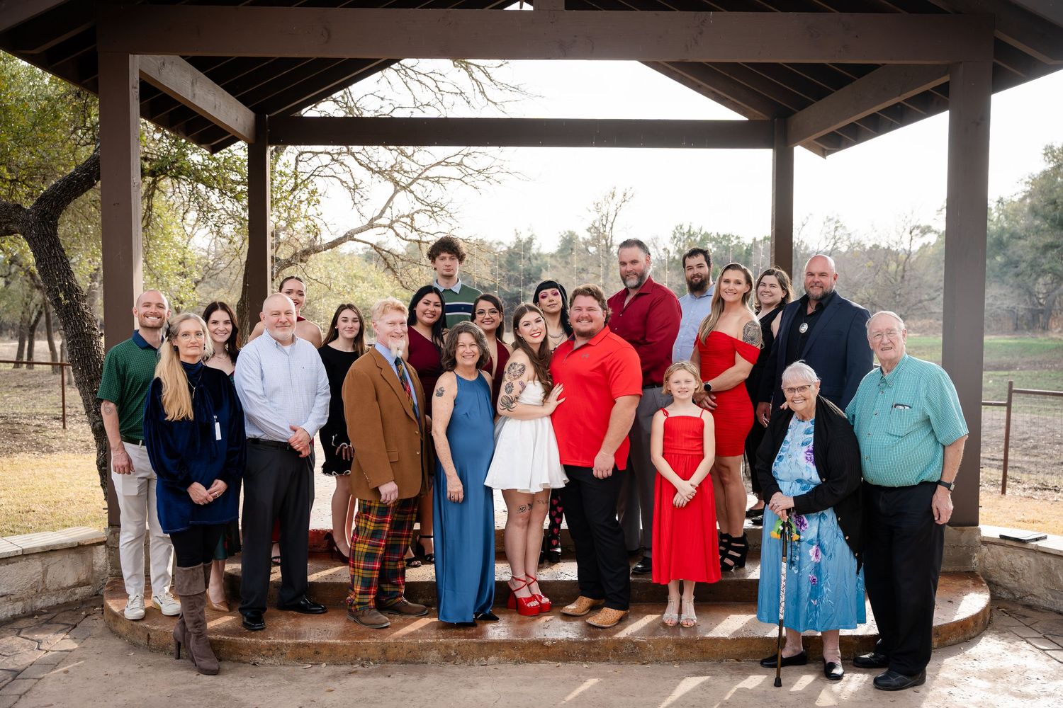 Large family group posing together under a wooden pavilion outdoors for a formal portrait photo.