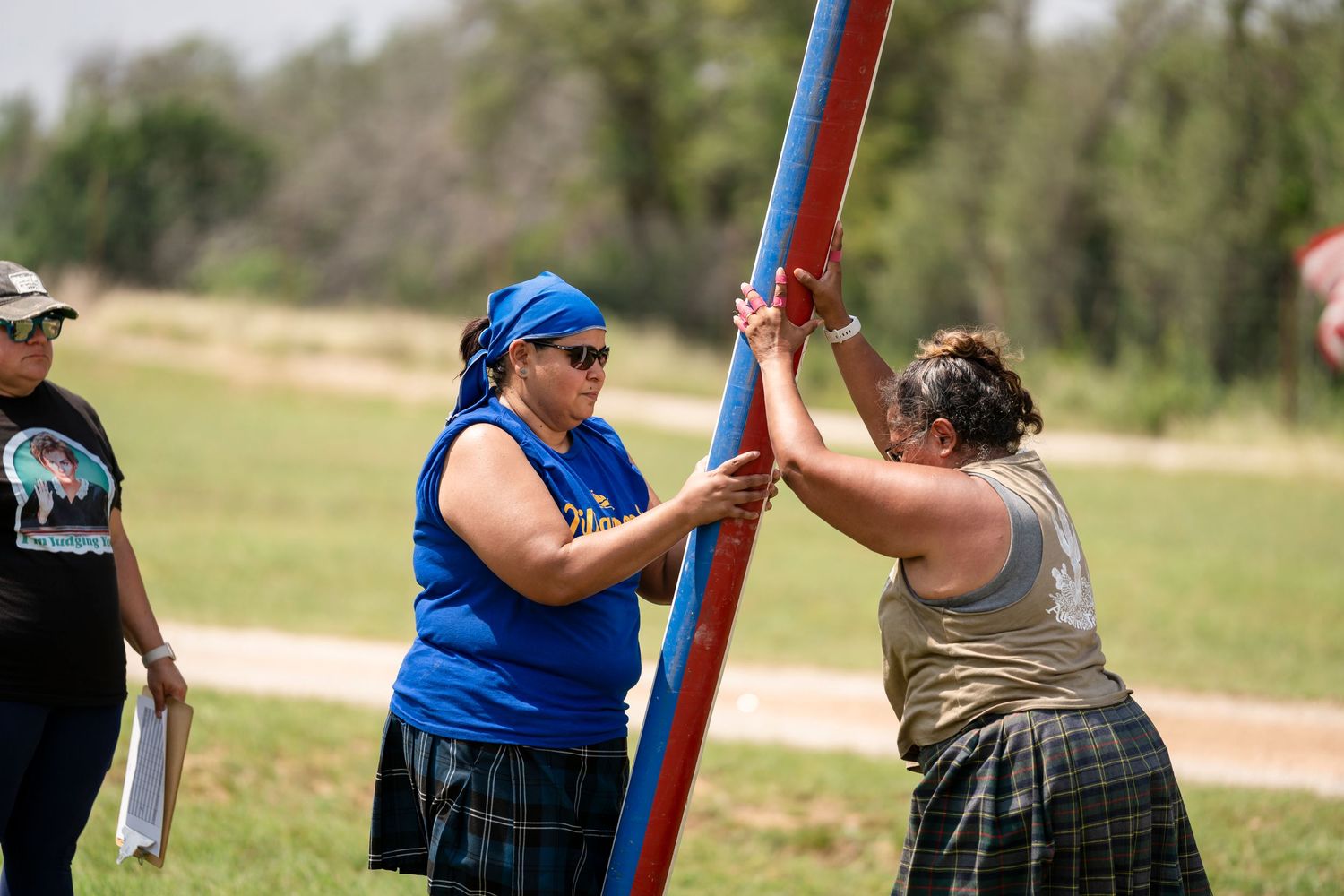 Two people practice sword fighting techniques outdoors with foam swords while wearing casual clothing.
