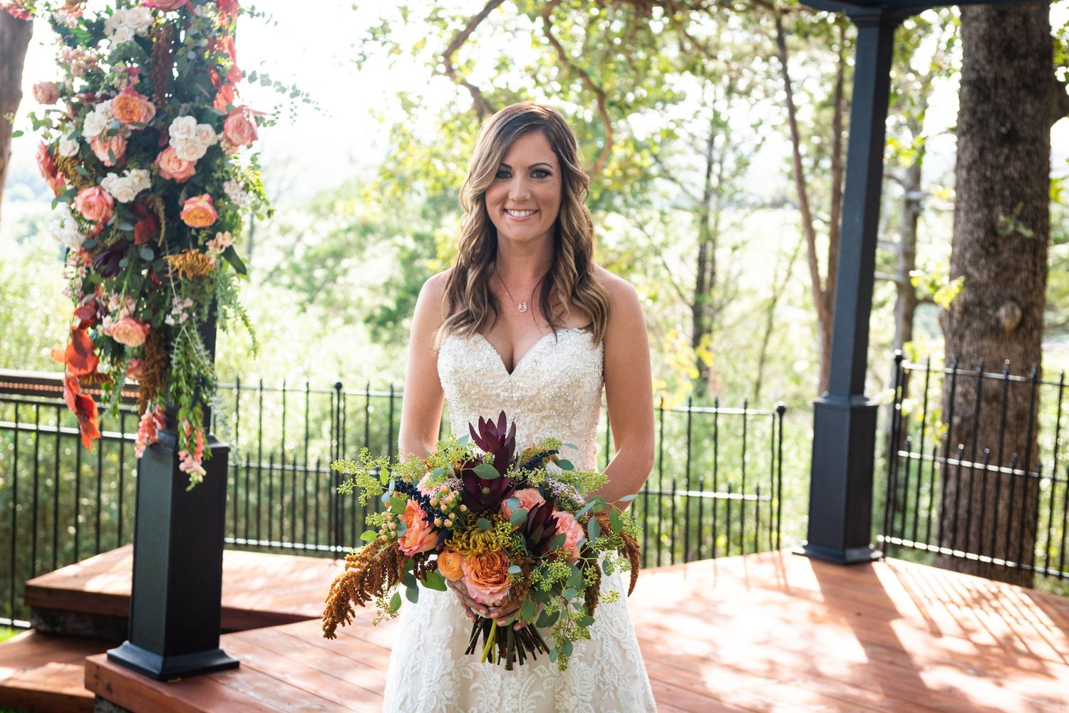 Outdoor bridal portrait with colorful floral arch and natural garden backdrop.