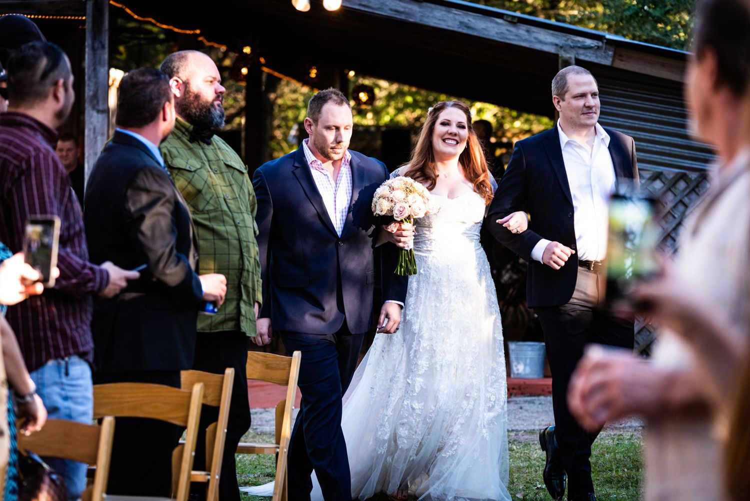 A traditional wedding ceremony procession walks down the outdoor aisle.