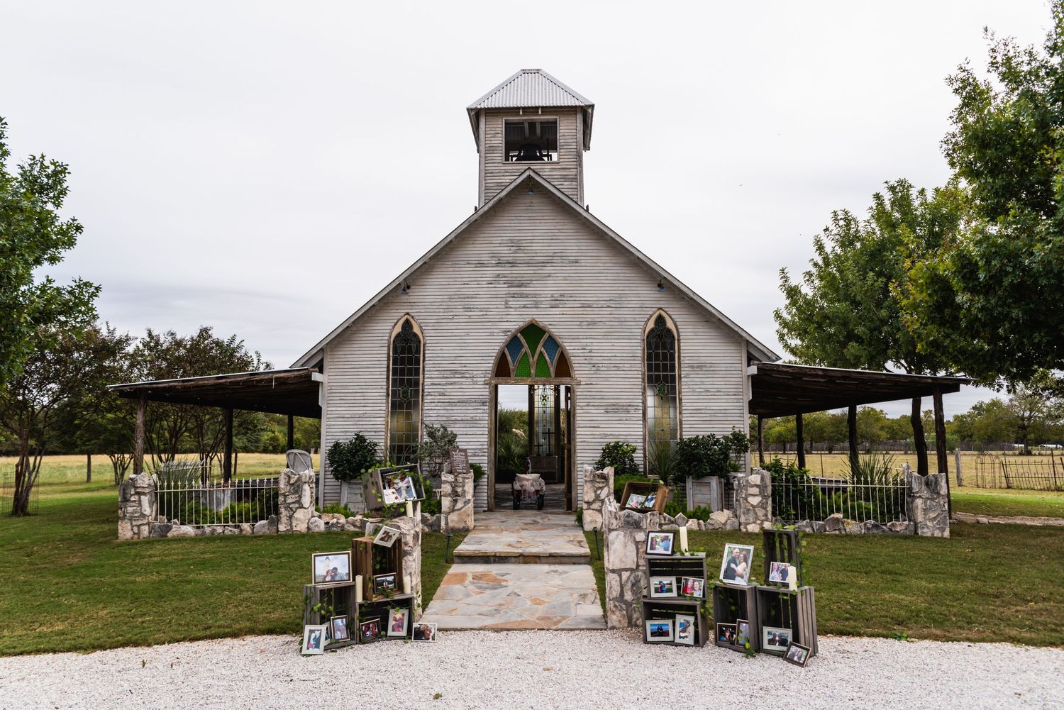 Rustic white chapel decorated for an outdoor wedding ceremony with floral arrangements and seating.