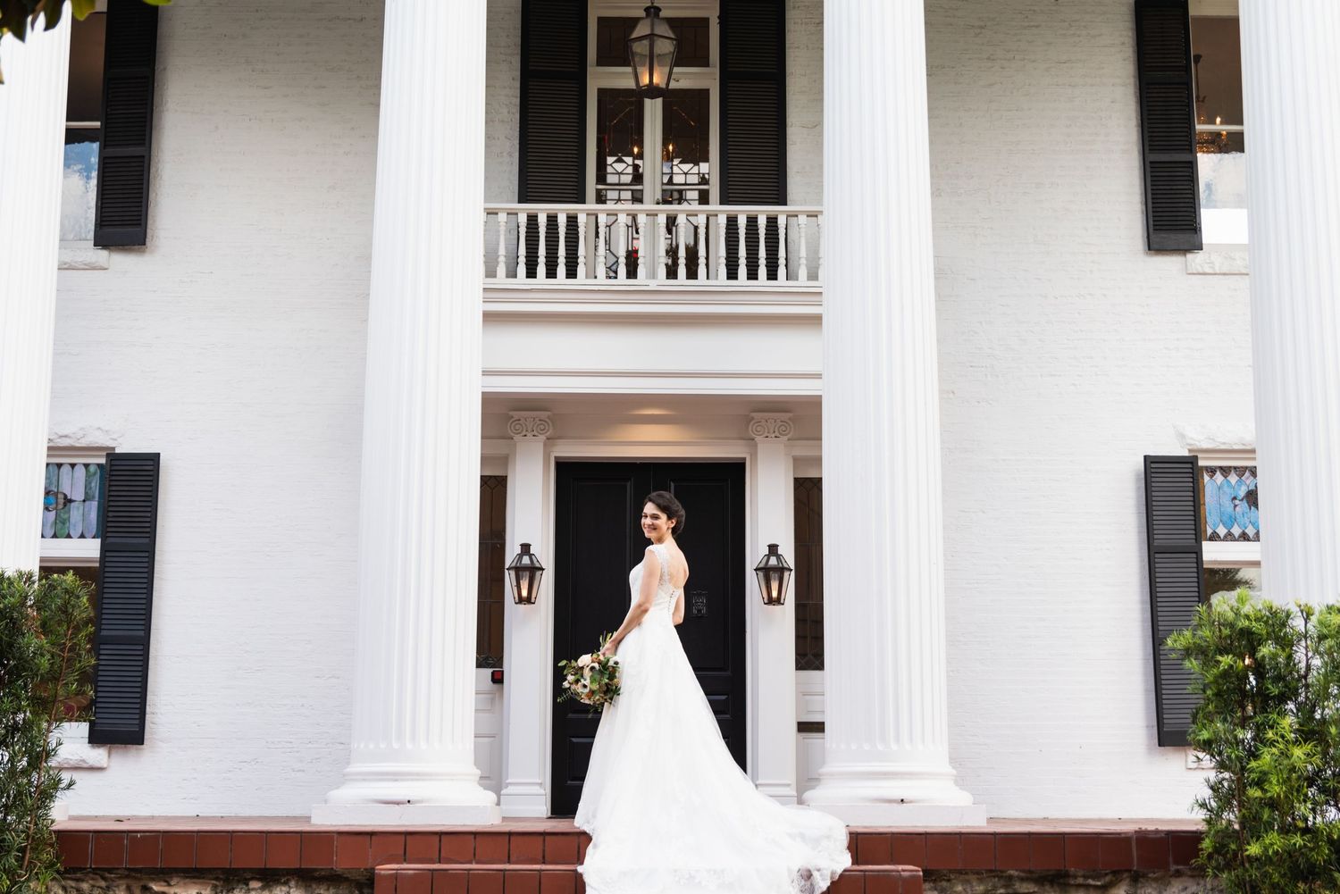 A stunning bridal portrait in front of a grand white colonial building with tall columns.