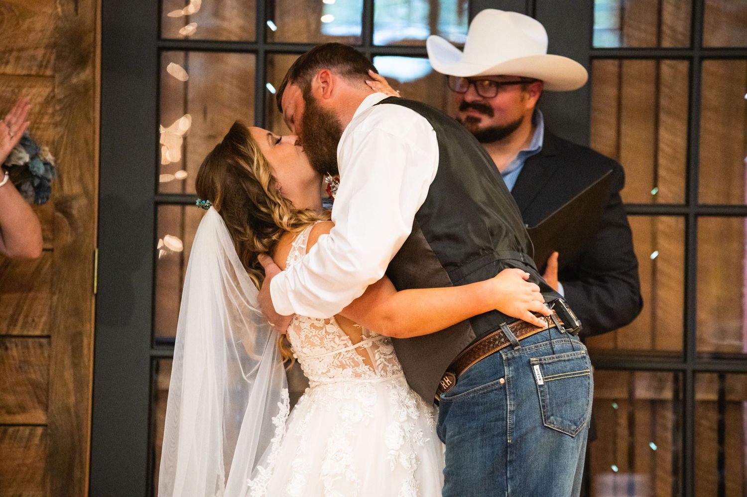 A romantic first kiss moment at a country-style wedding ceremony.
