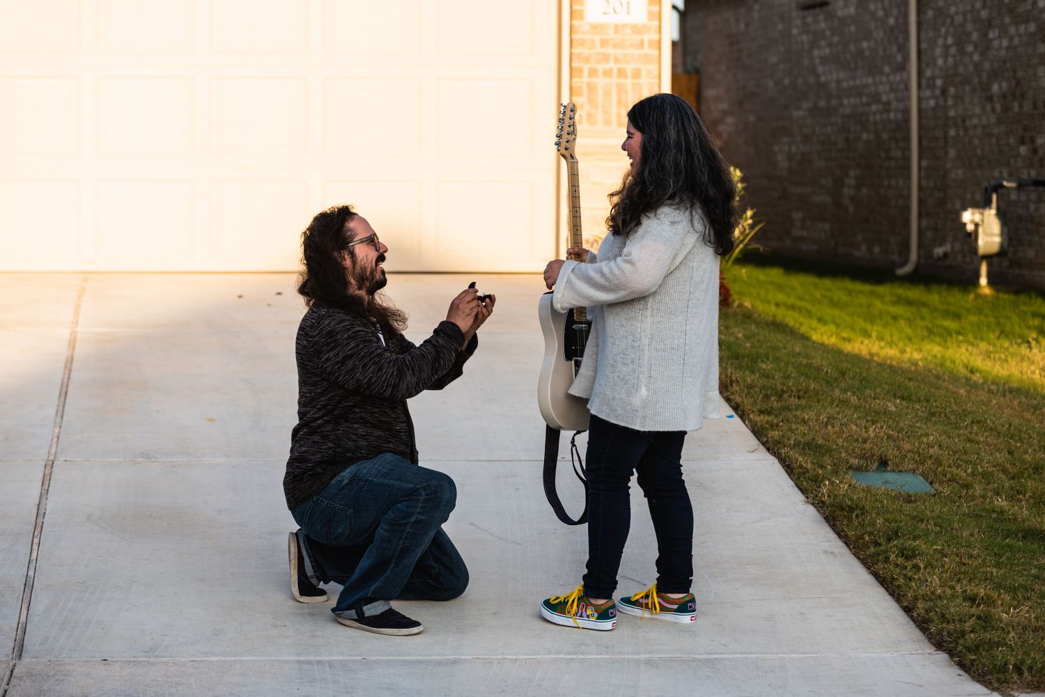 A touching proposal moment captured outdoors with a guitar in hand.