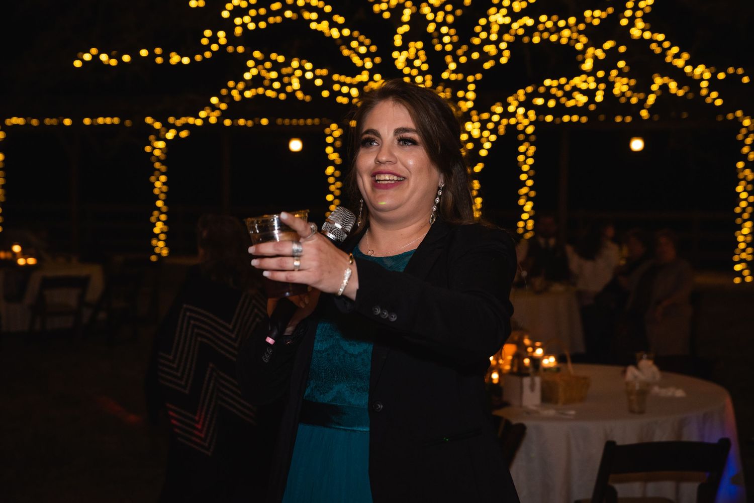 Guest enjoying drinks and dancing at an outdoor wedding reception with fairy lights.