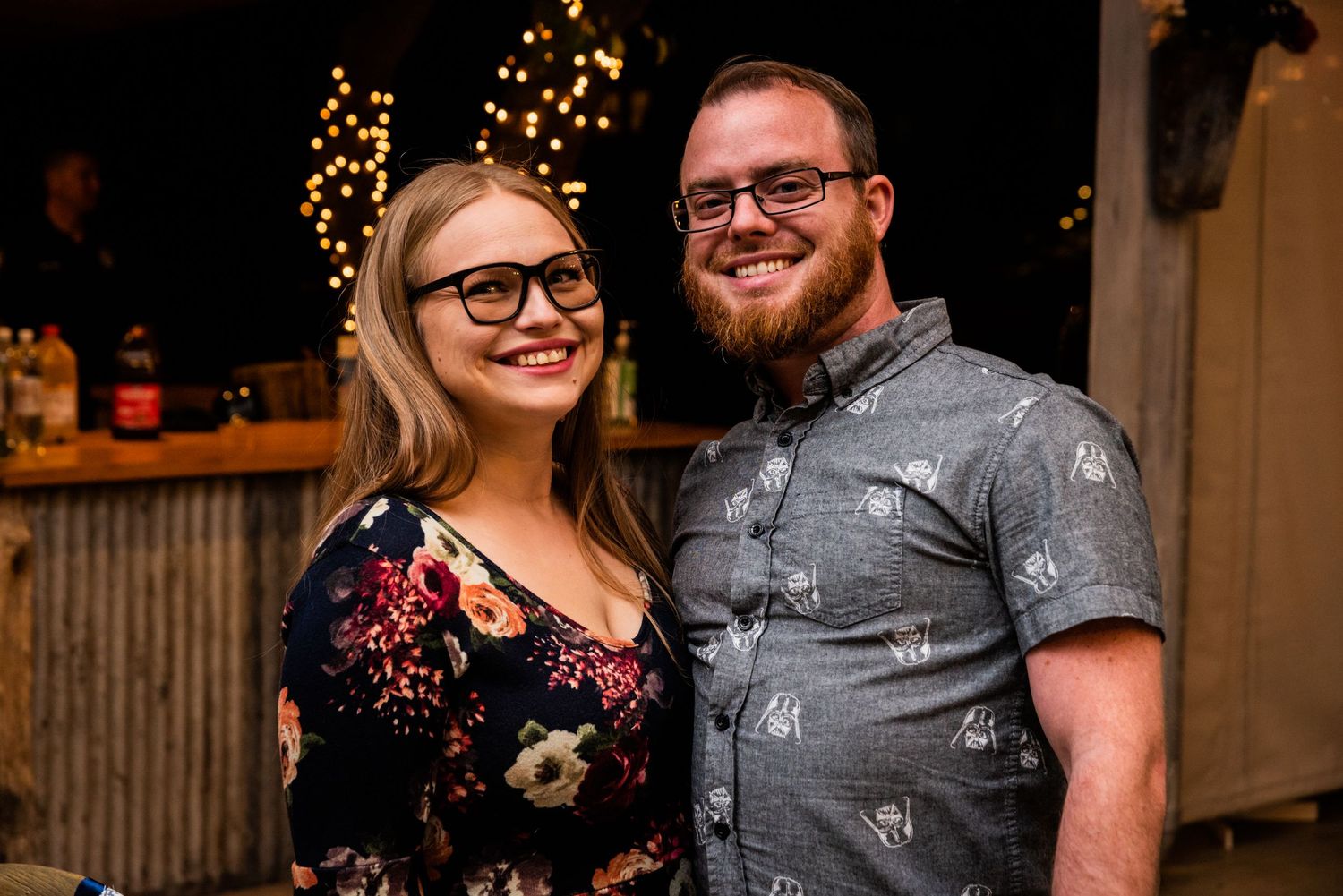 A casual evening portrait at an outdoor venue with string lights in the background.
