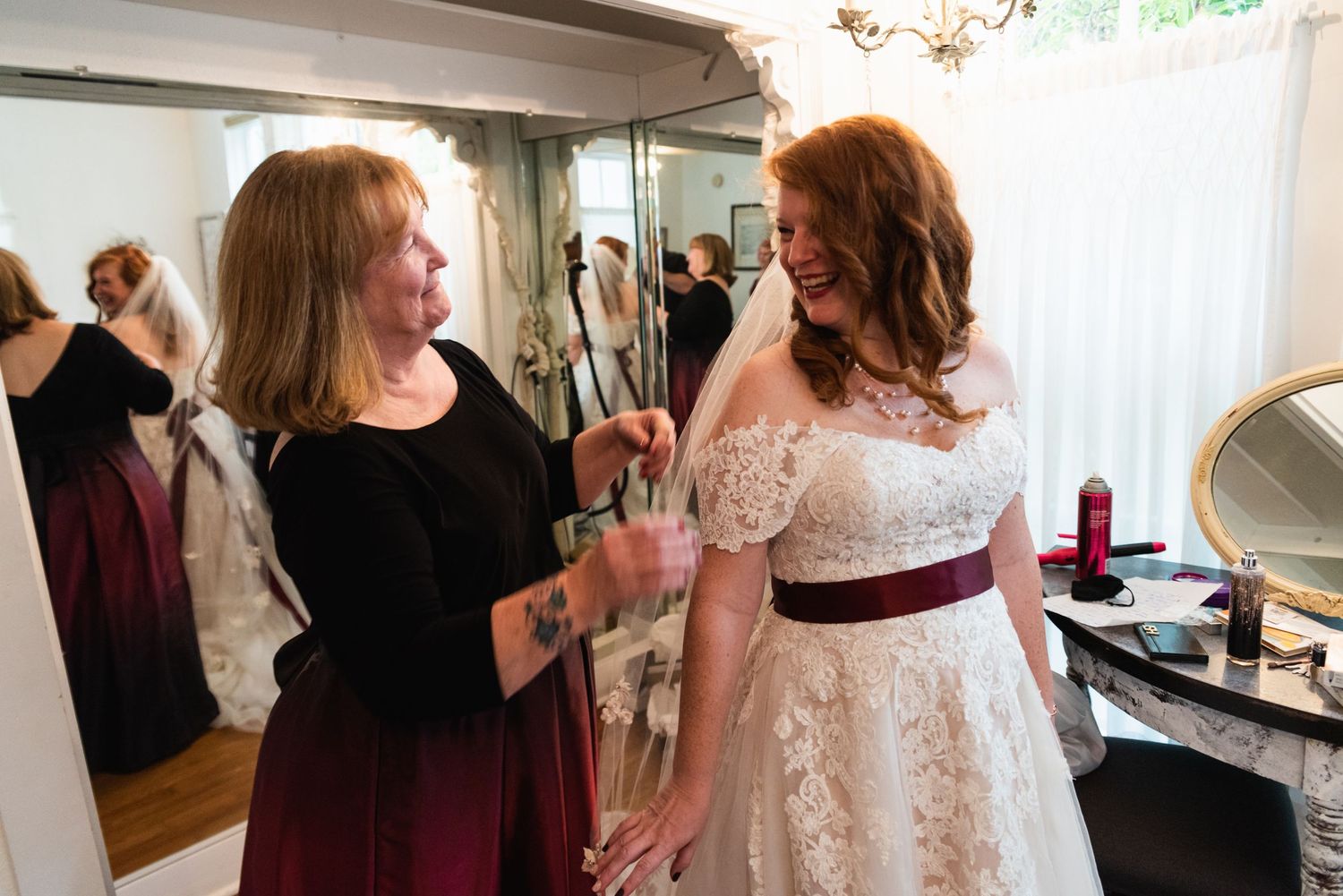 Wedding preparation scene with burgundy and white dresses in a dressing room.