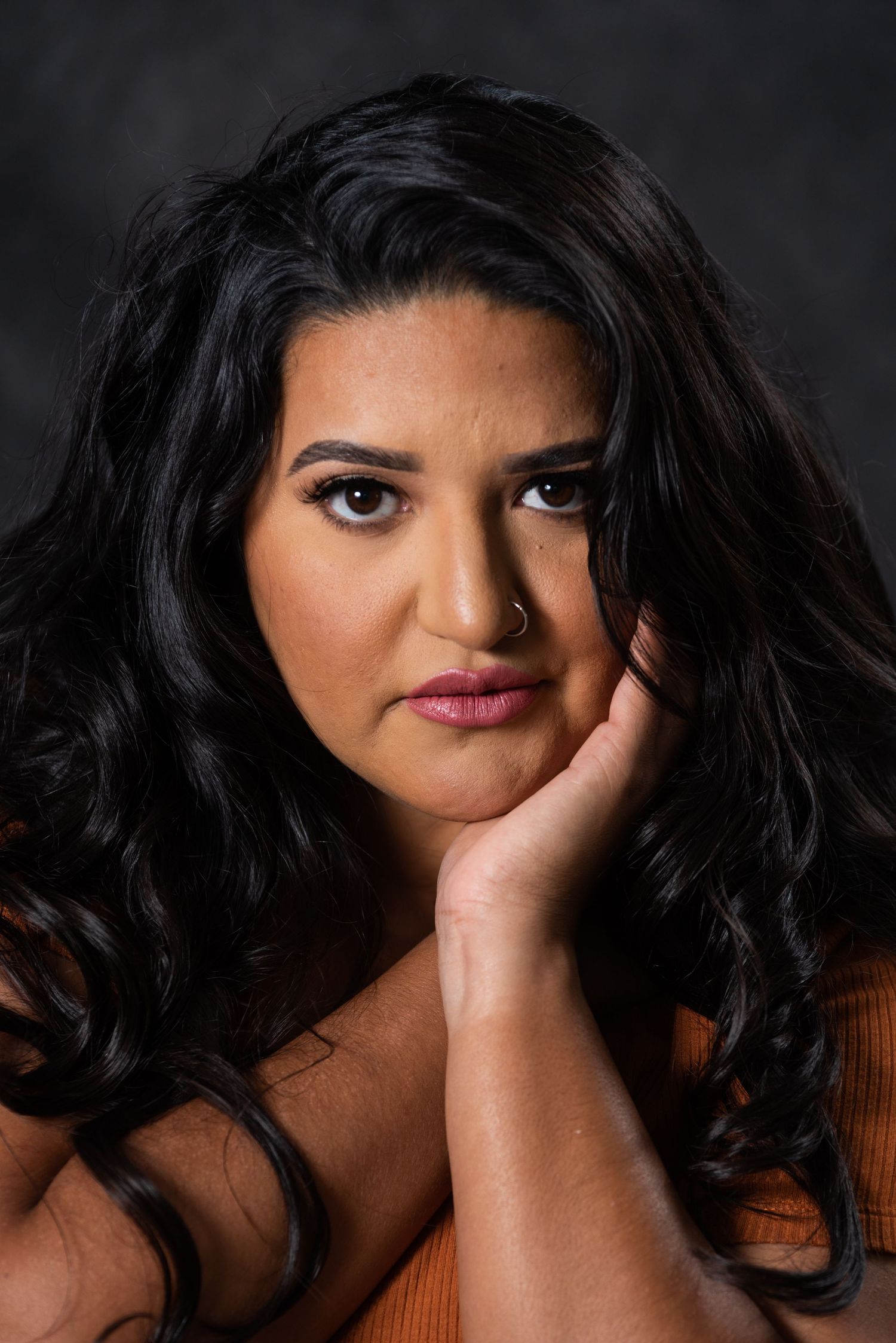 Close-up beauty portrait of woman with dark hair against black background.