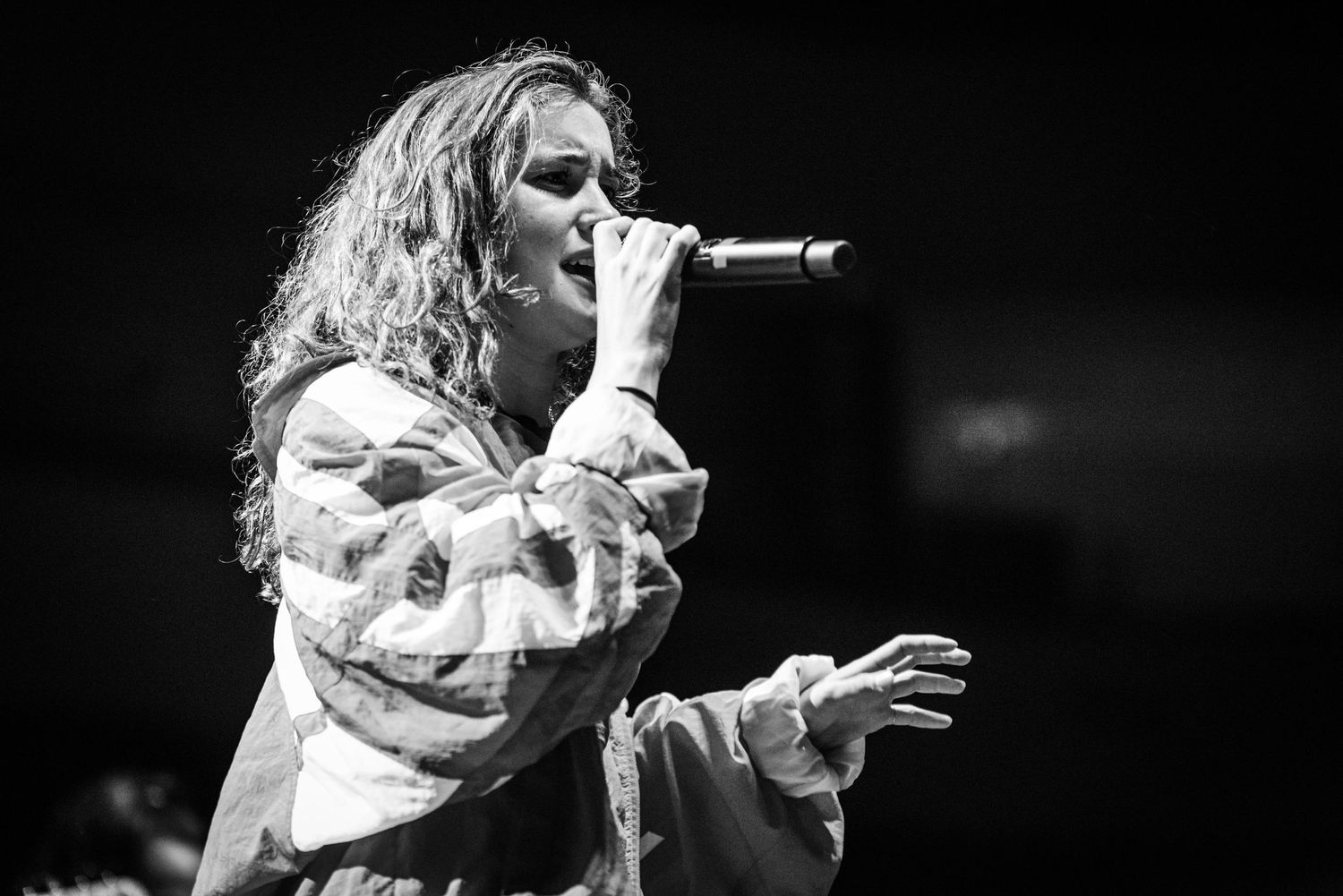 Black and white concert photo showing an energetic vocal performance on stage.