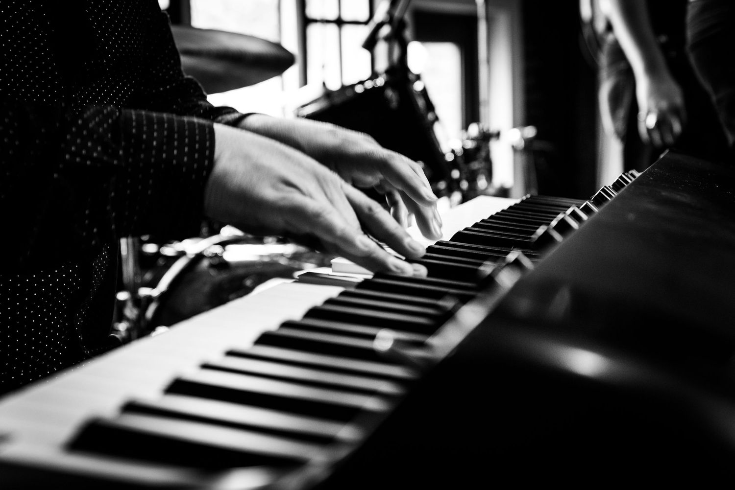 Close-up black and white shot of hands playing piano keys during live performance.