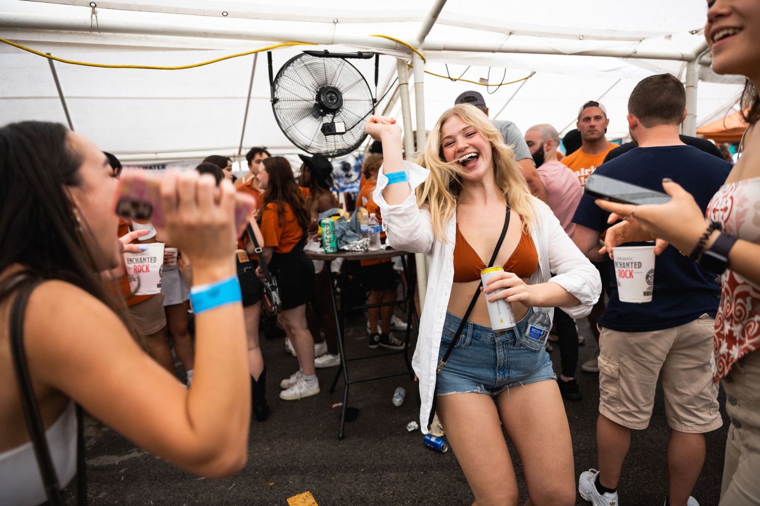Friends laughing and taking photos at a lively outdoor celebration.