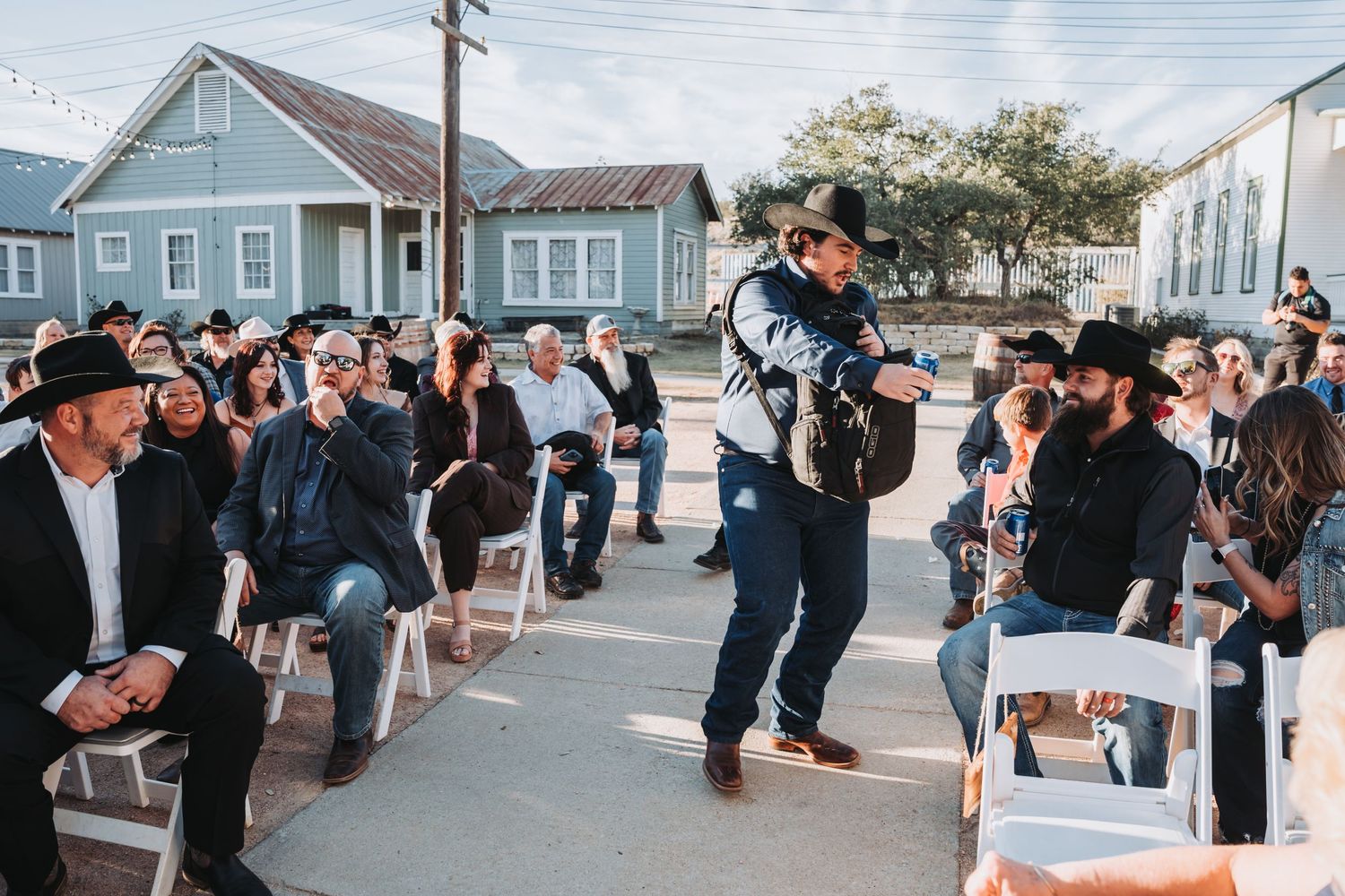 A performer in cowboy attire walks through rows of seated guests at an outdoor event.