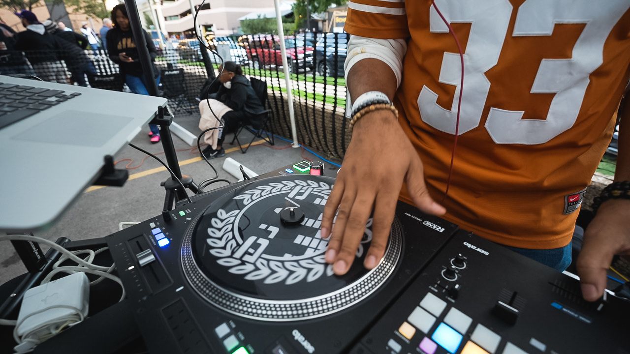 Close-up of DJ equipment and turntable with Texas football jersey visible in frame.