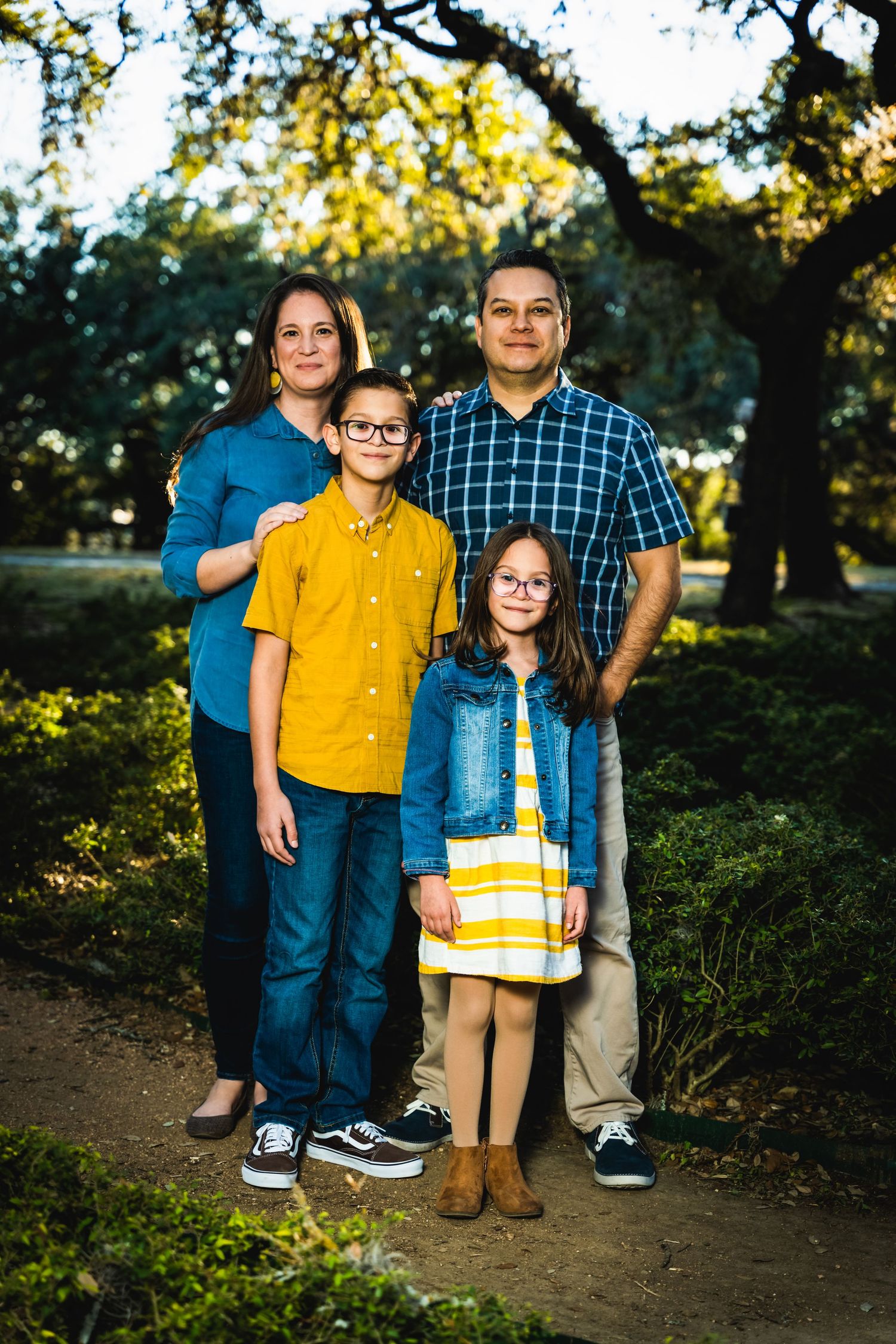 Family portrait taken at sunset under large oak trees on a dirt path.