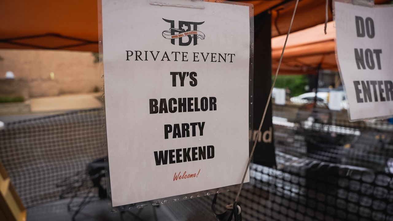 Close-up of sign showing 'TYS Bachelor Party Weekend' details at private event.
