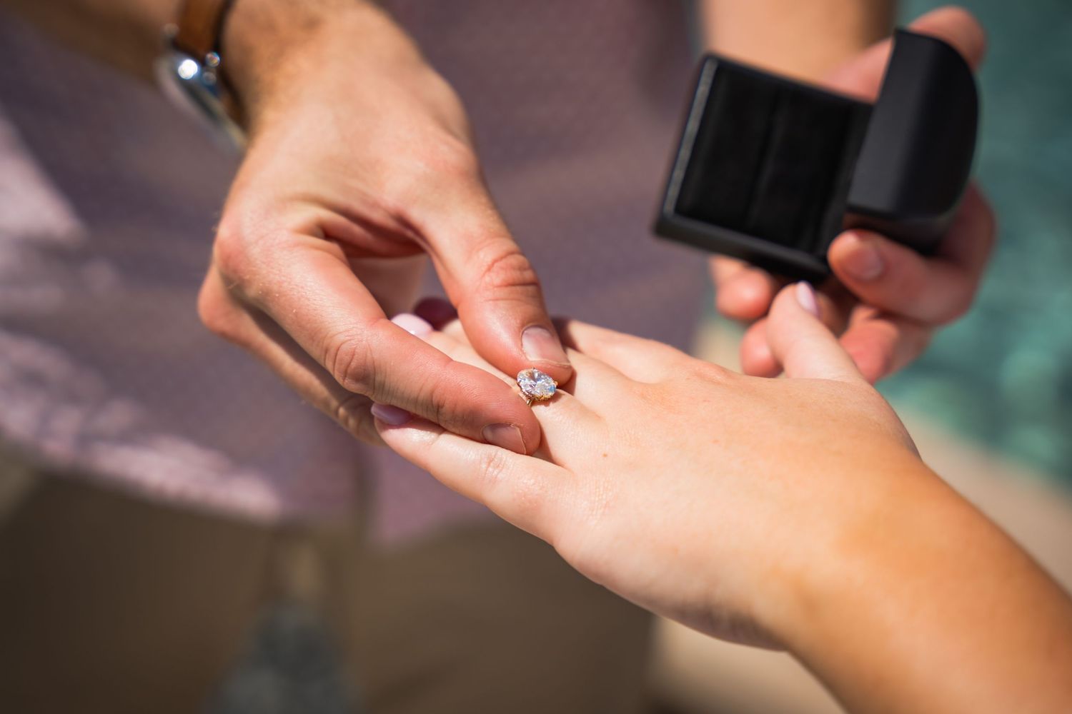 A close-up shot of hands during a ring exchange at an engagement.