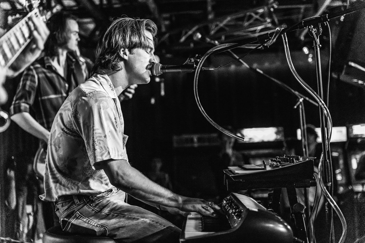 A black and white photo of a musician performing at a piano on stage.
