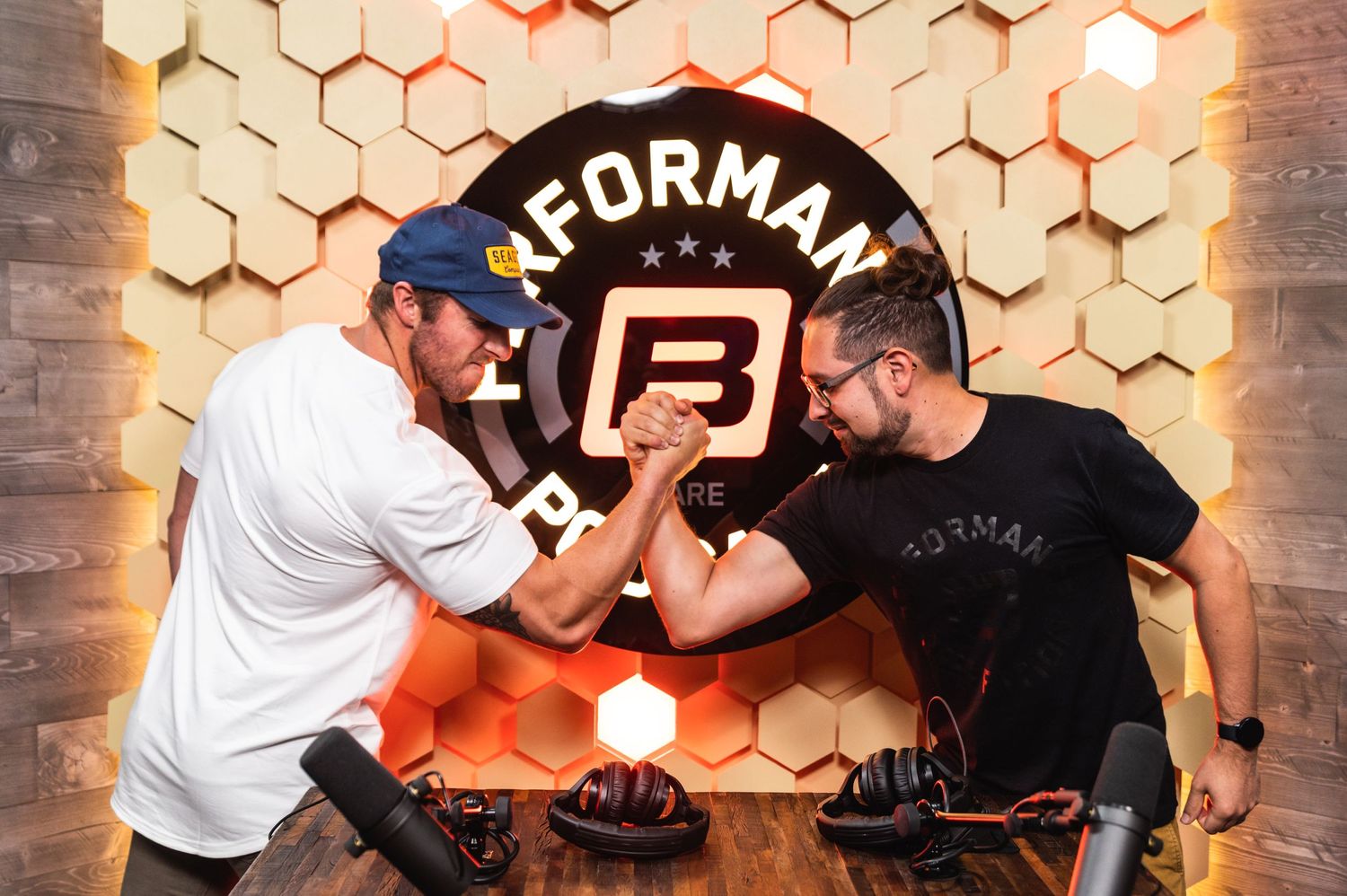 Two people arm wrestling in front of illuminated Performance B podcast logo.