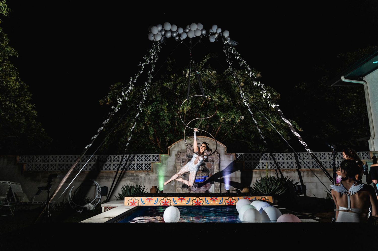 Nighttime aerial performance with white balloon decorations and ambient lighting effects.