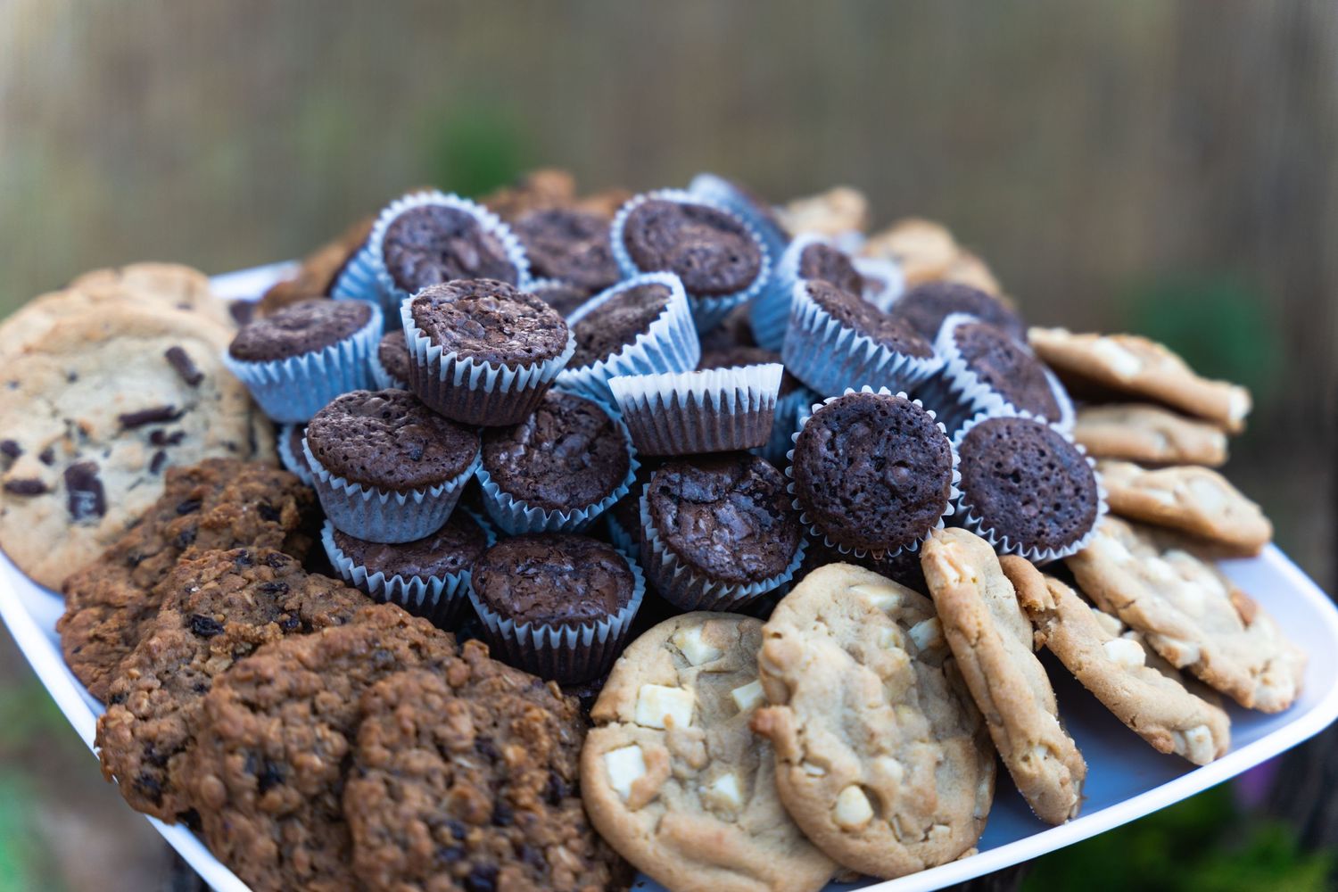 Plate of chocolate sandwich cookies and assorted desserts at a celebration.