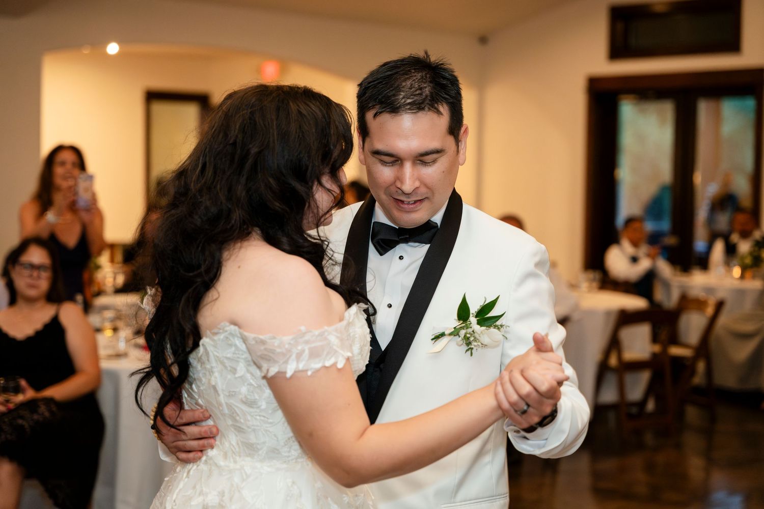 Wedding couple twirls gracefully on the dance floor at an indoor reception venue.