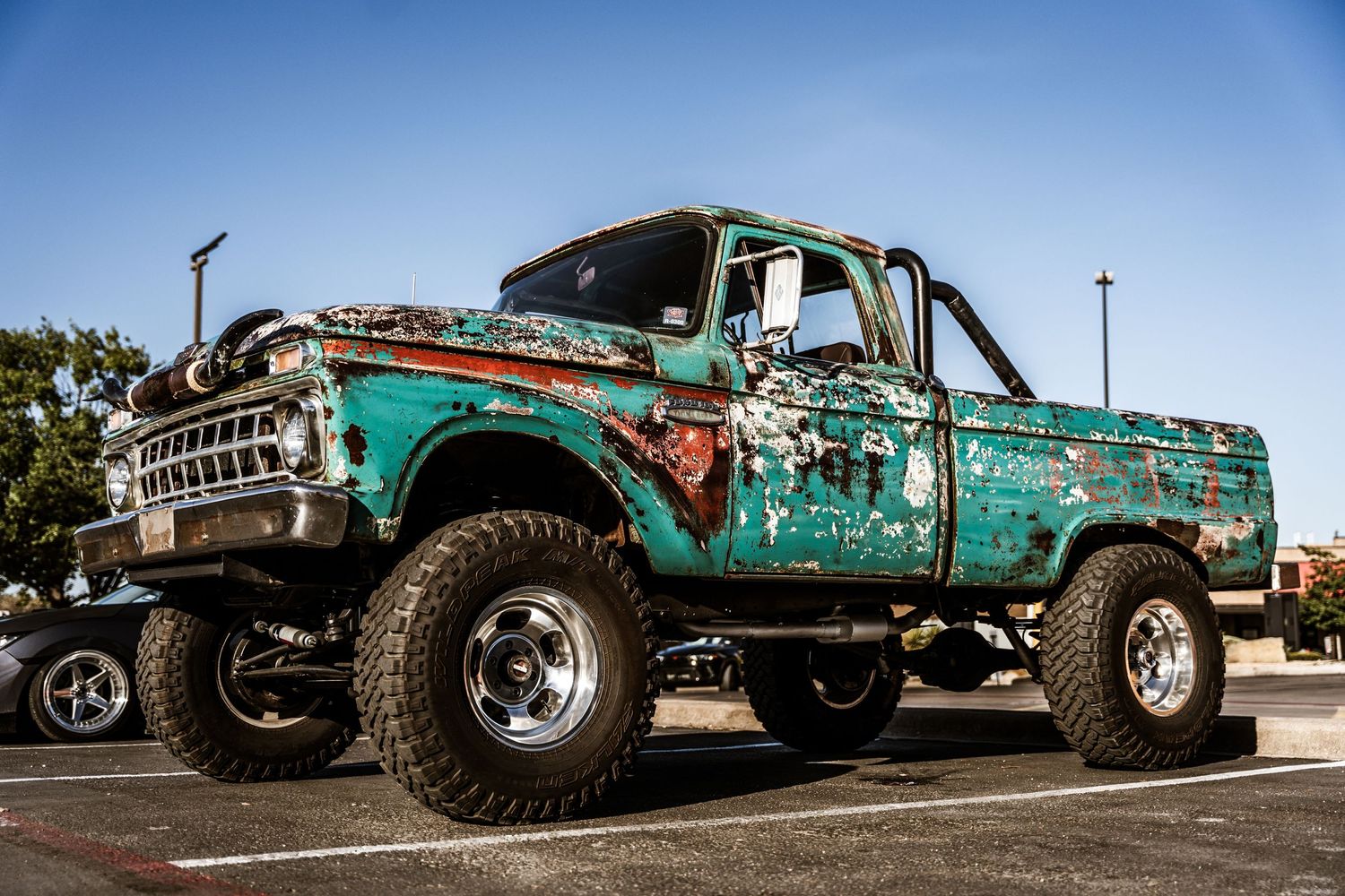 Lifted vintage Ford pickup truck in turquoise with rusted patina finish.
