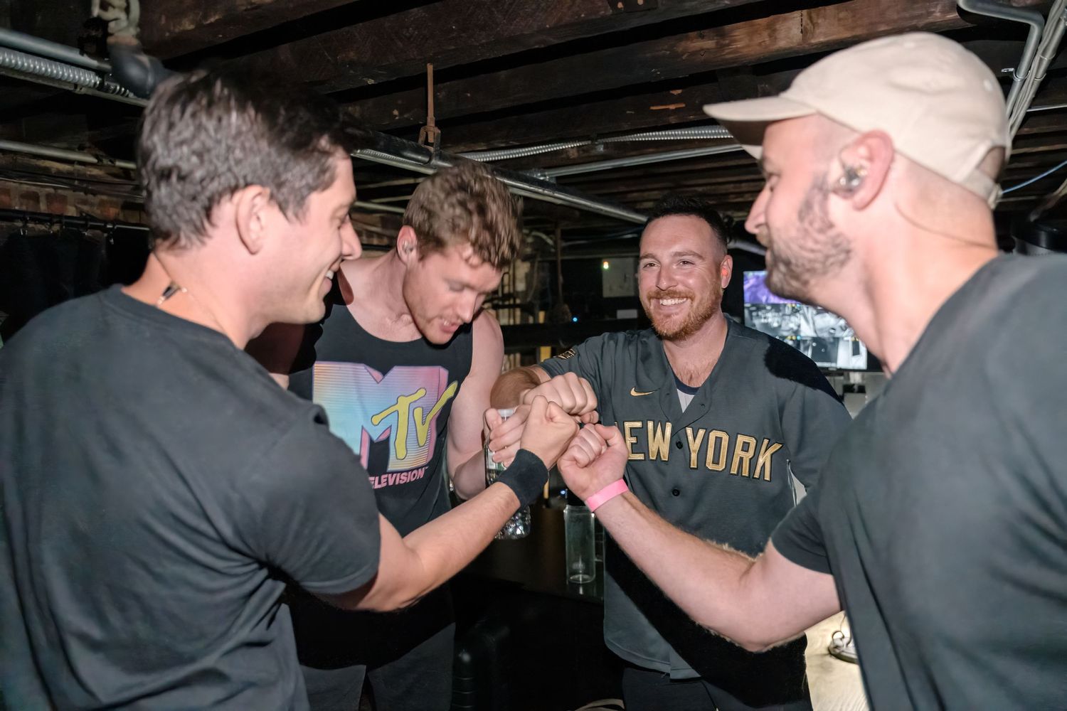Group celebrating and greeting each other enthusiastically in a dimly lit venue.