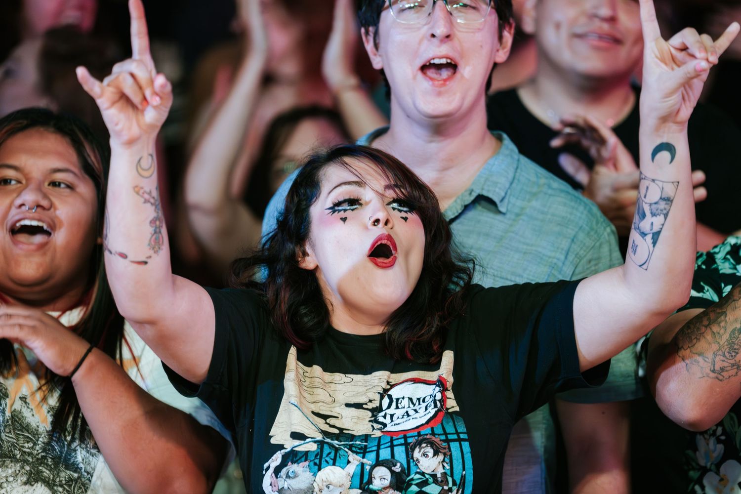 Energetic fans cheering and raising arms during live music performance.