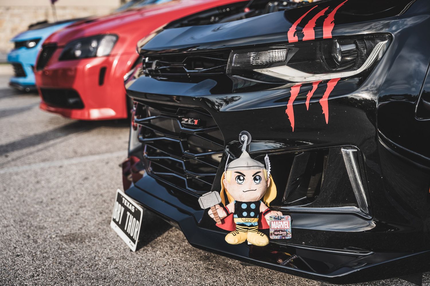Custom car front grille with decorative Thor toy mounted on the bumper.