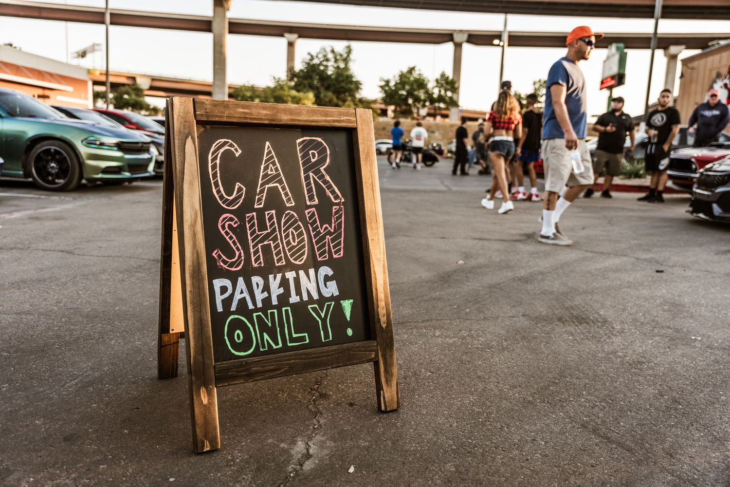 Wooden A-frame sign at car show reading 'Car Show Parking Only' in chalk lettering.