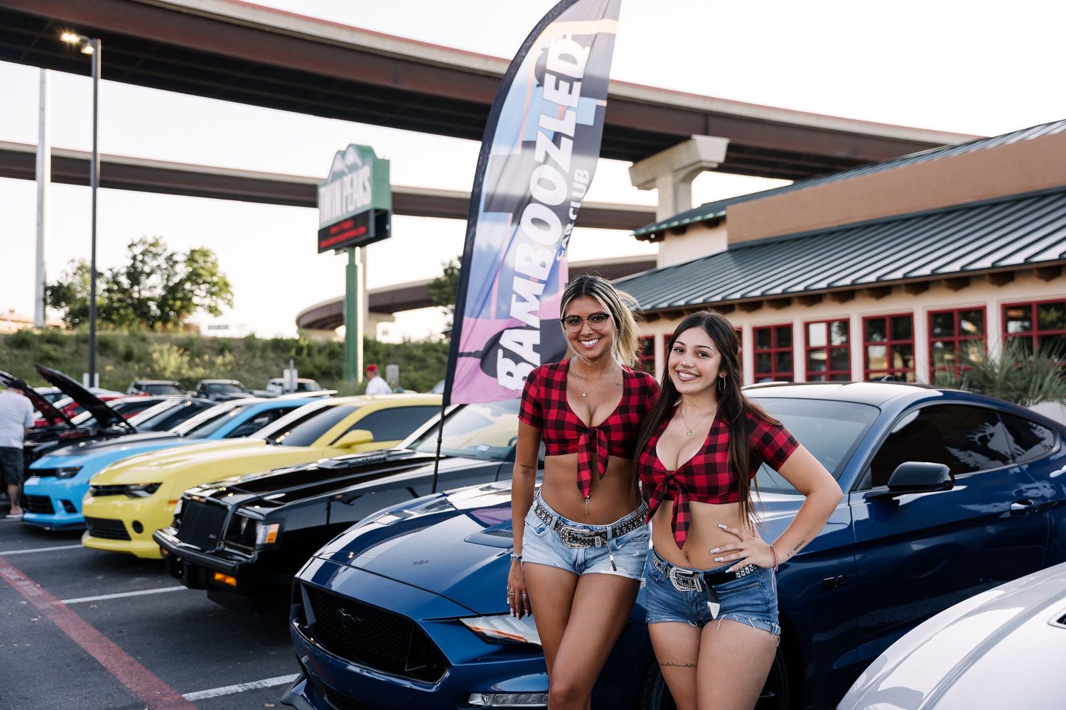 Car enthusiast meet featuring colorful modified vehicles lined up in a parking lot.