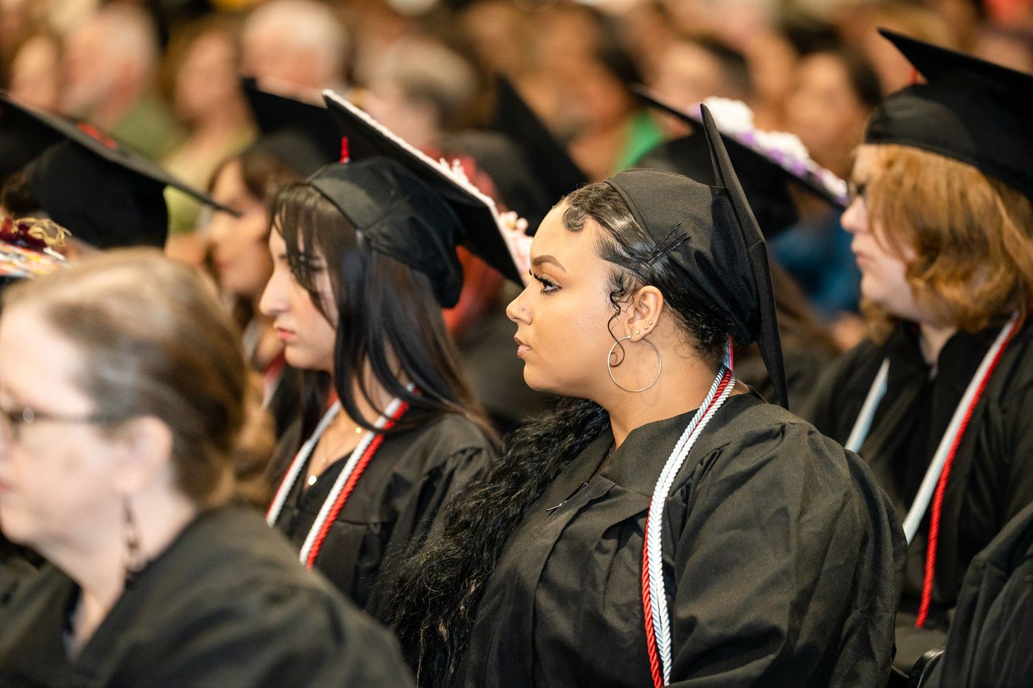 Graduates in black caps and gowns seated during a commencement ceremony.