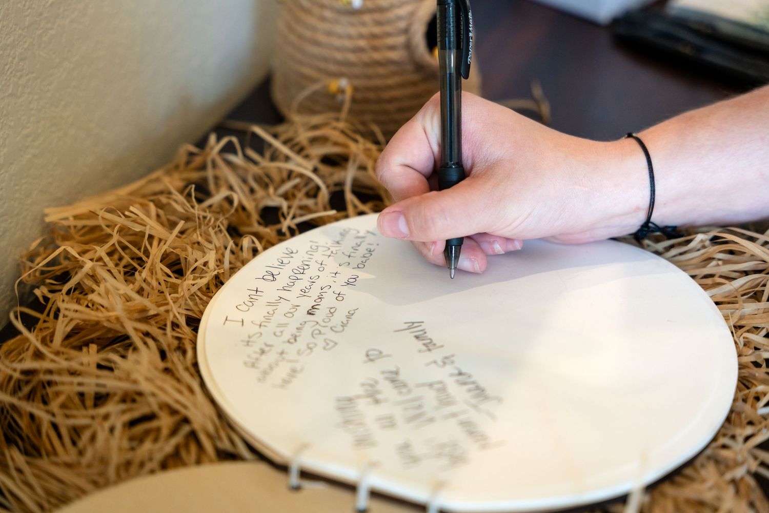 Hand writing on decorative plate with raffia table decor.