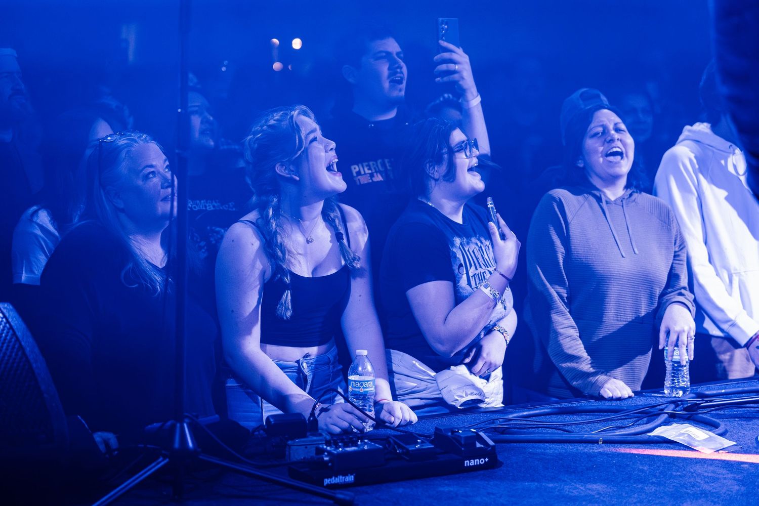 Concert attendees enjoy a show under blue stage lighting.