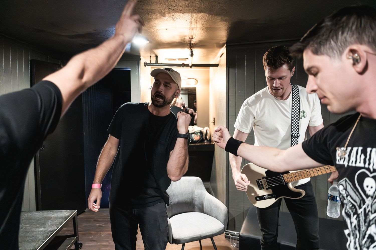 Band members interact in a cramped backstage hallway before performance.