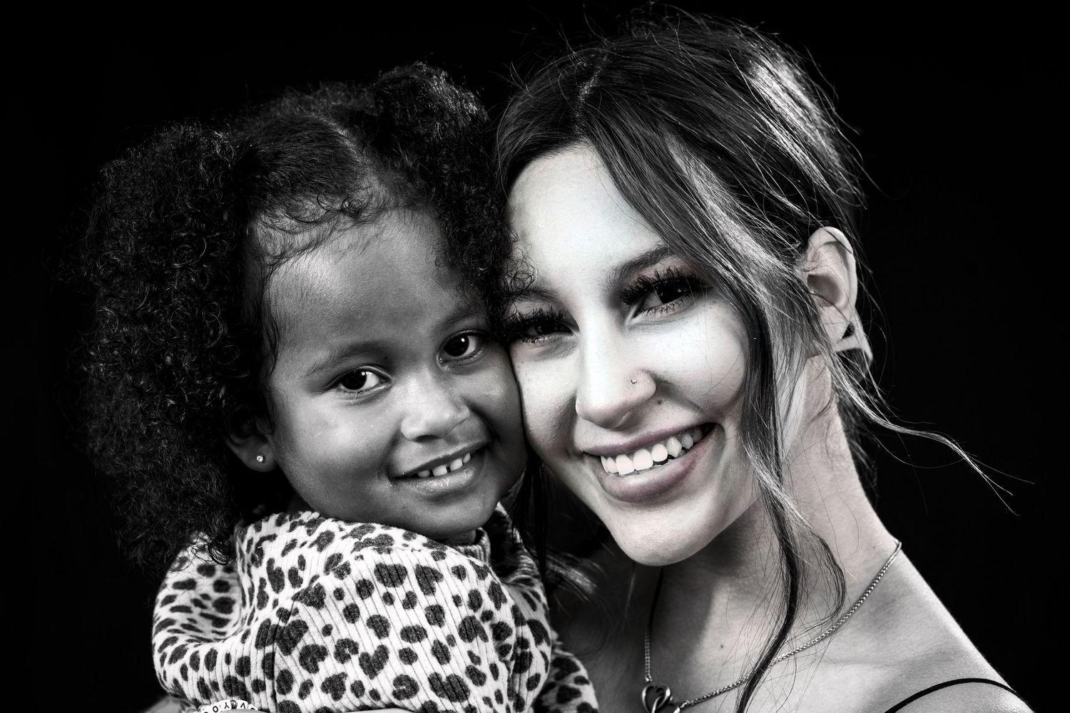 Intimate black and white photograph capturing tender moment between child and woman.