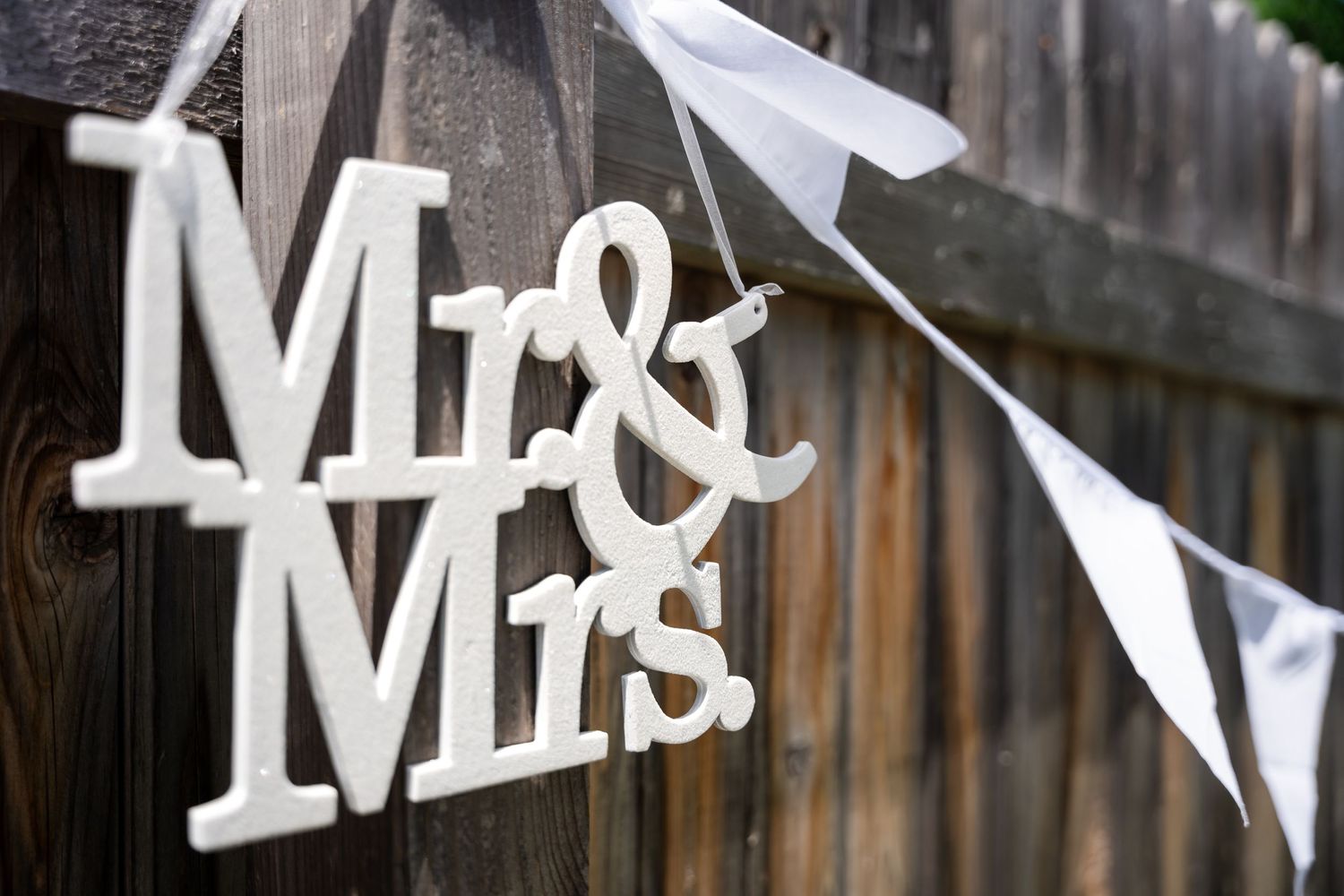 White 'Mr & Mrs' sign with bunting decorates a rustic wooden fence.