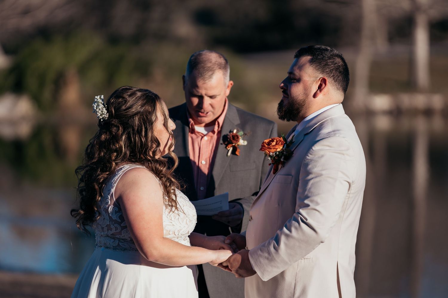 Intimate outdoor wedding ceremony by waterfront with officiant.